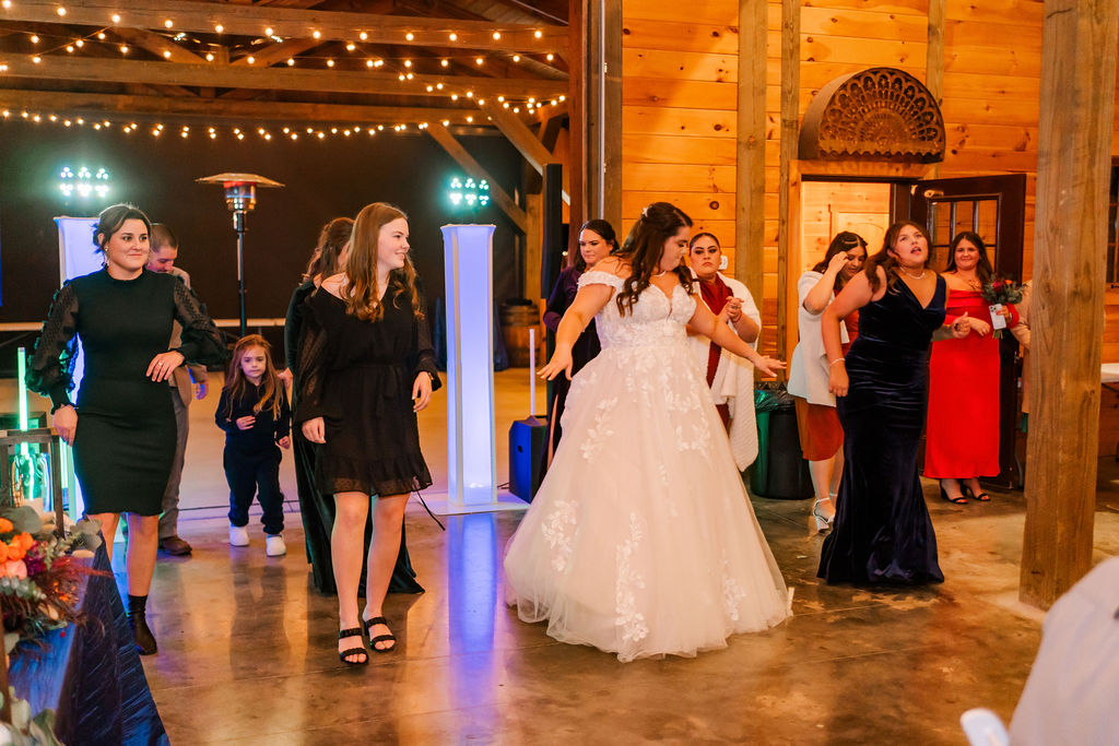 Courtney dances arms open under string lights among guests at Courtney & John's Covey Creek reception.