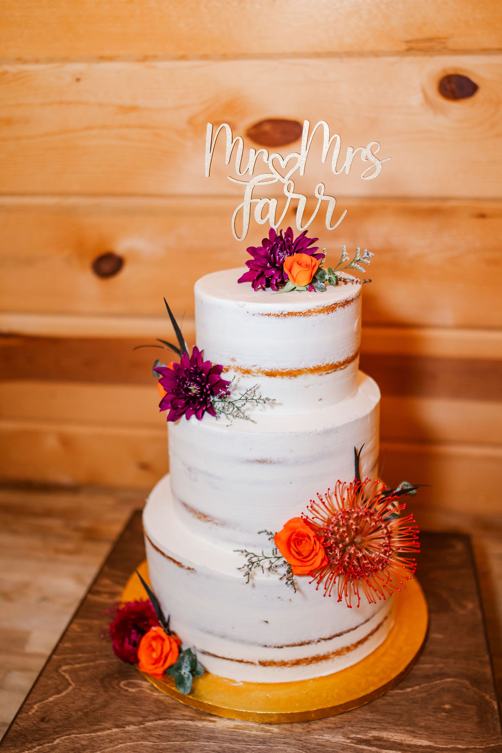 Courtney & John's three-tier semi-naked cake with orange and purple florals and Mr & Mrs topper at Covey Creek.