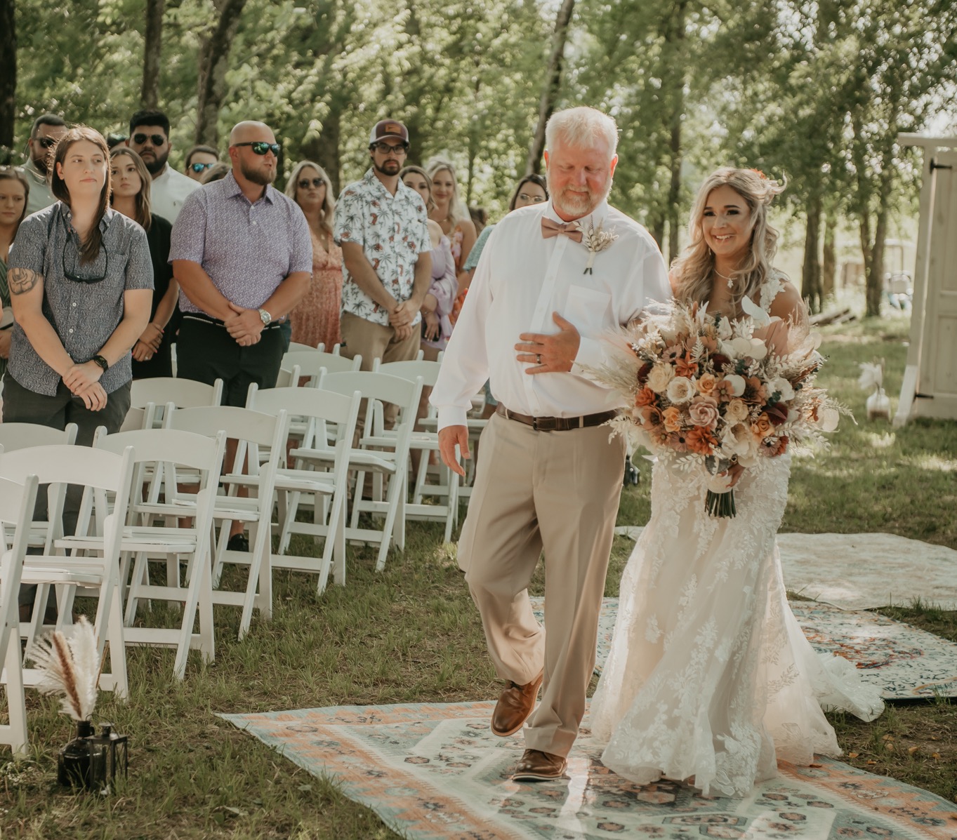 Hali walks the Covey Creek aisle with her father, warm bouquet in hand, during Hali & Kyle’s wedding.