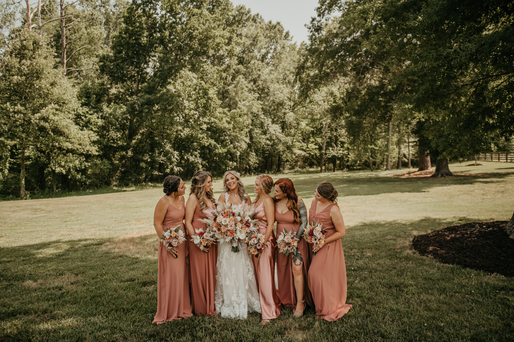 Hali poses with bridesmaids in terracotta gowns on the lawn at Covey Creek during Hali & Kyle’s wedding.