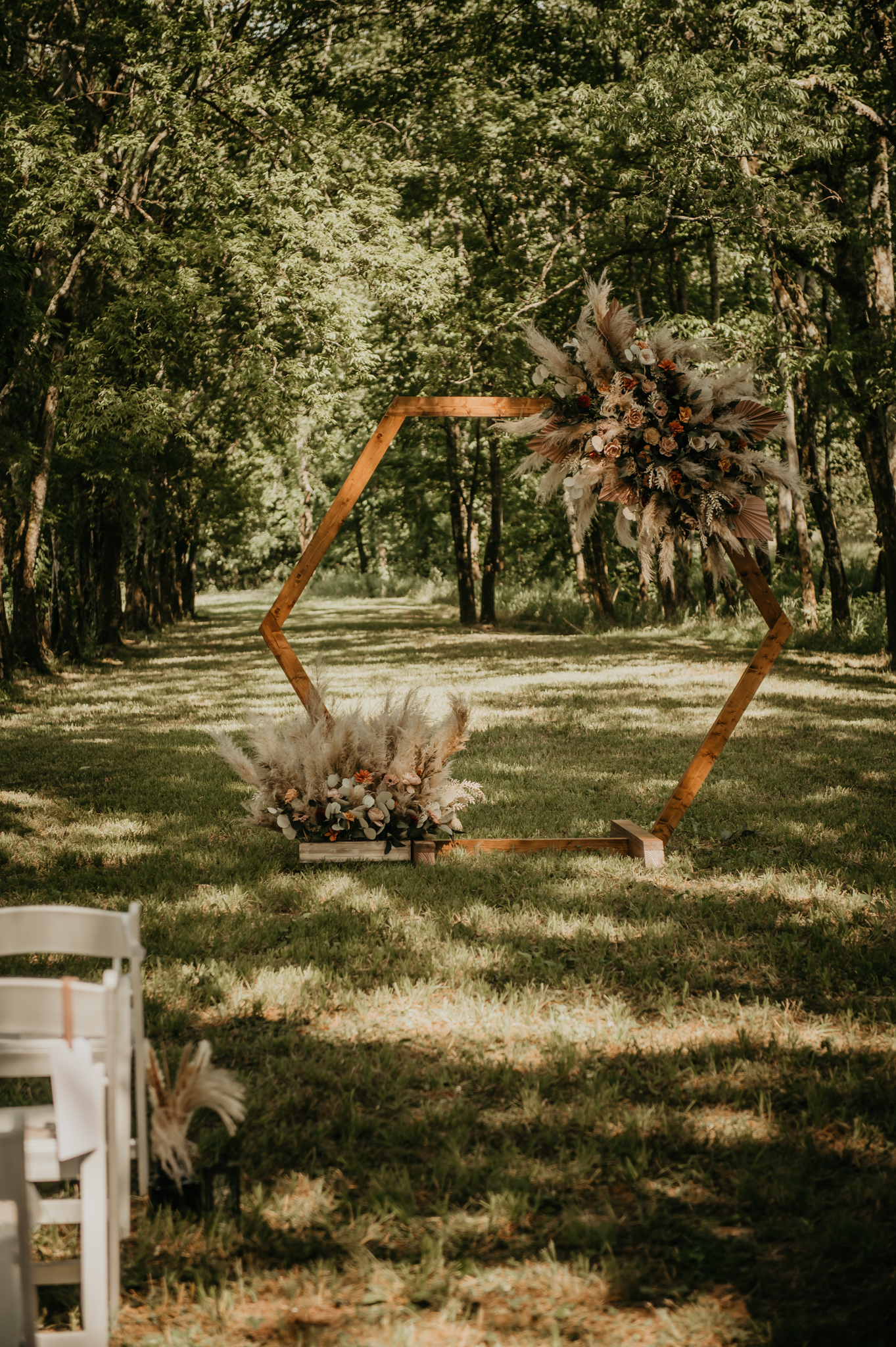 Hexagonal wooden arbor with pampas and terracotta florals set for Hali & Kyle’s ceremony at Covey Creek.