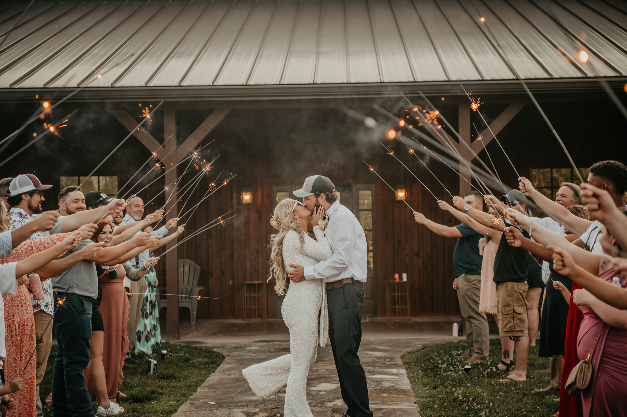 Hali & Kyle kiss under a sparkler arch outside the barn at Covey Creek during their evening send-off.