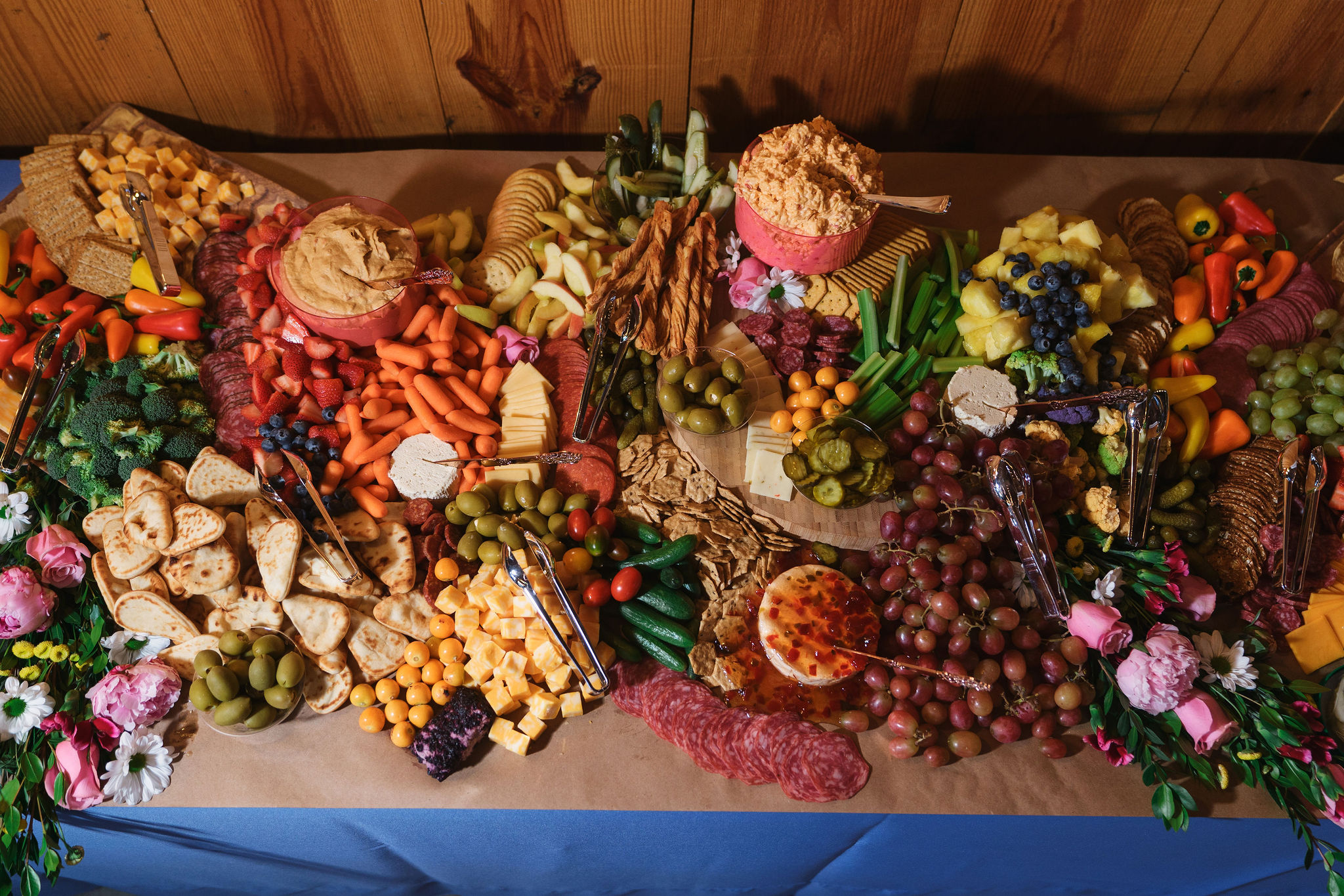 Ana & Carter charcuterie grazing table with cheeses, fruit, and pink florals in the barn at Covey Creek