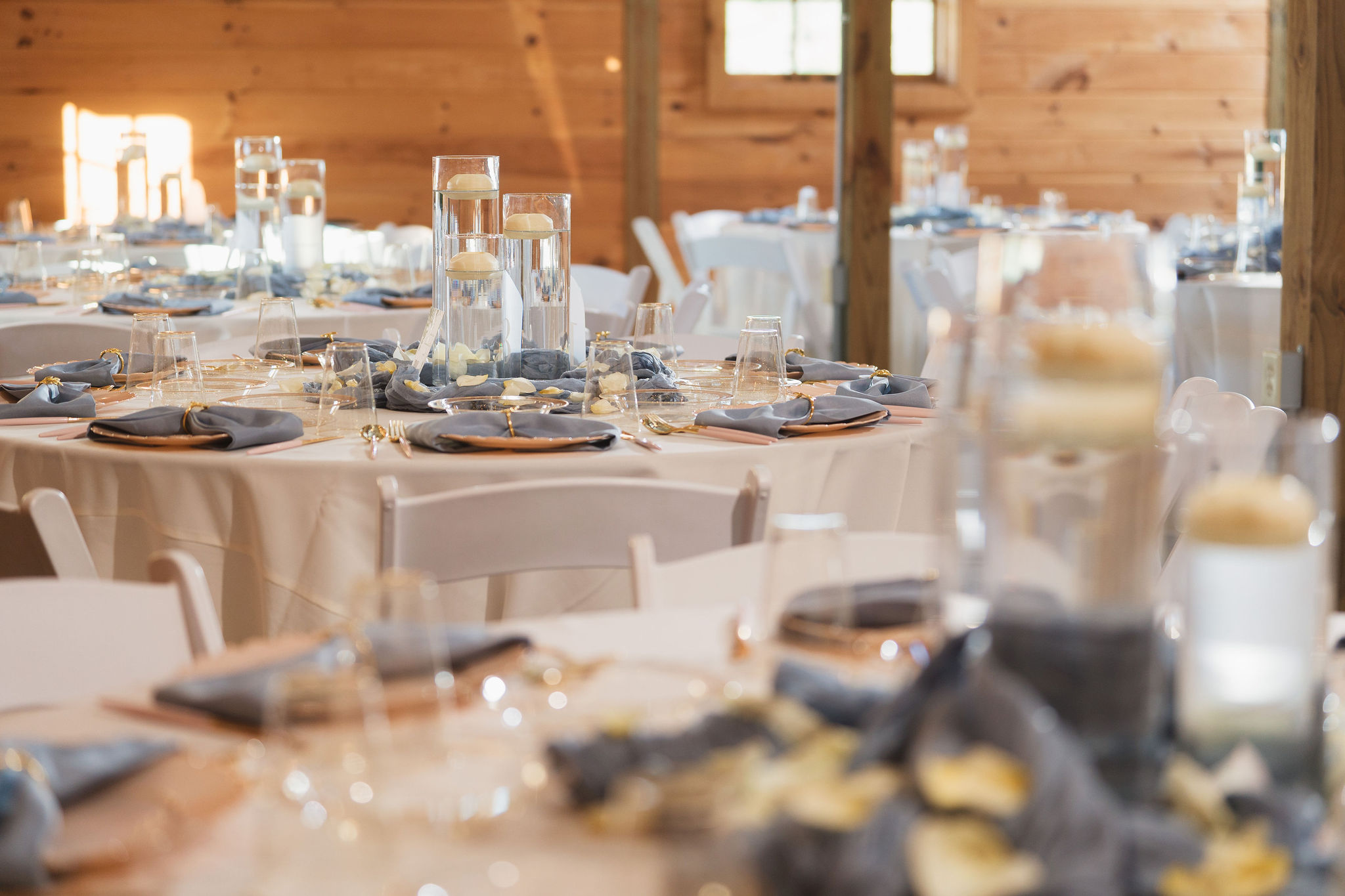 Ana & Carter reception tables with dusty blue napkins, gold chargers, and floating candles at Covey Creek