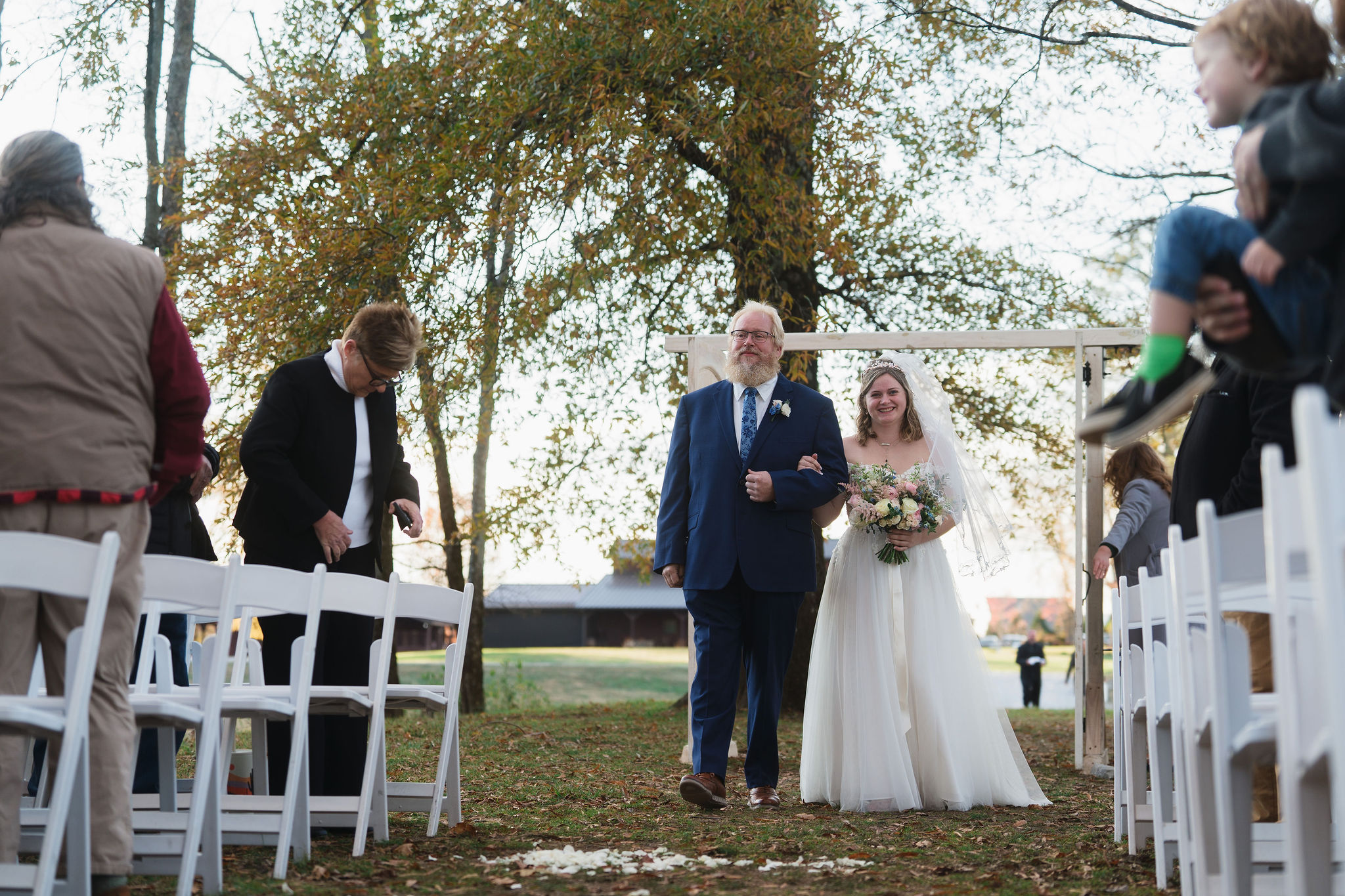 Ana & Carter: Ana walks the petal-strewn aisle with her father toward the barn at Covey Creek