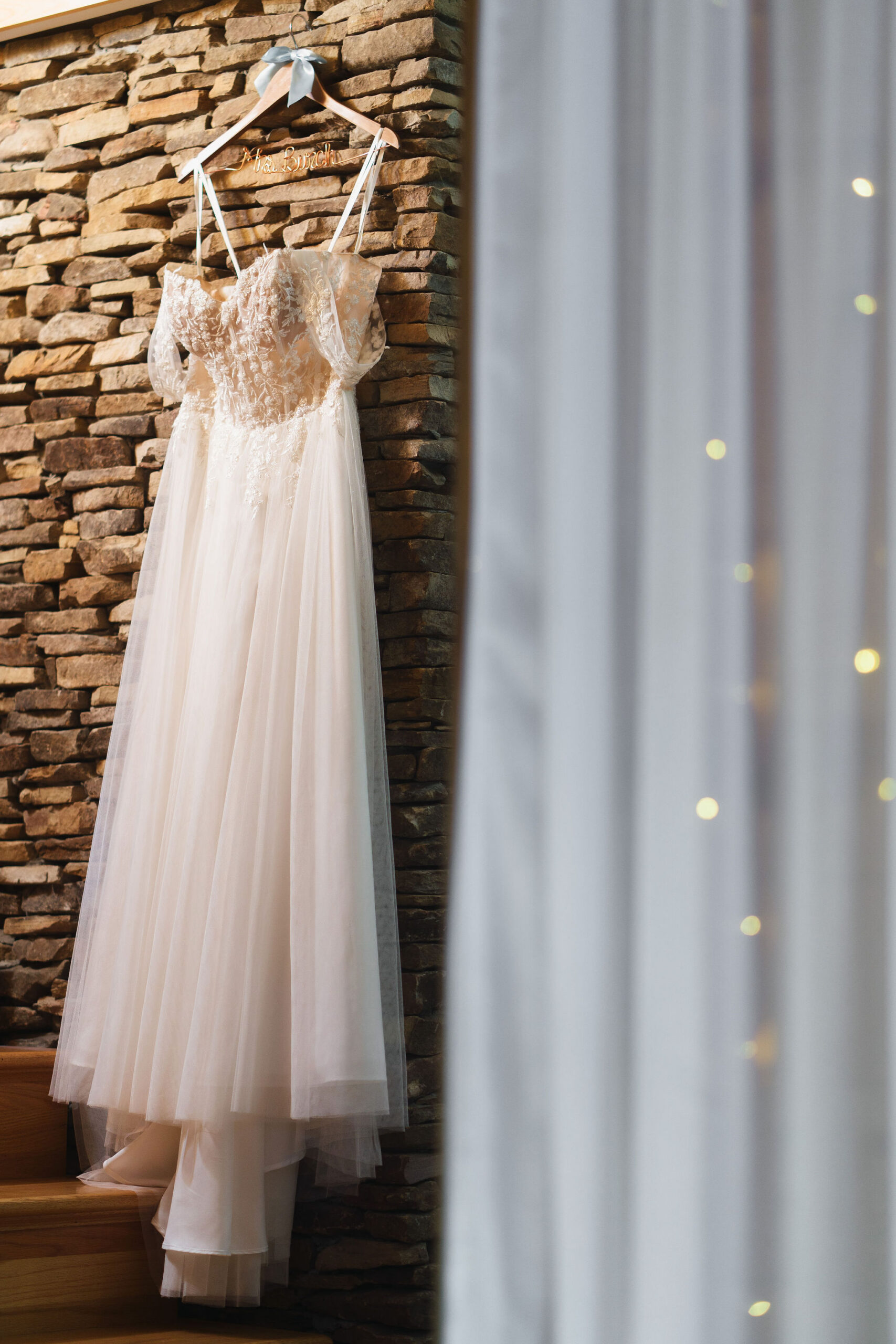 Ana & Carter: Ana's lace gown hangs on a Mrs. Smith hanger against a stone wall at Covey Creek