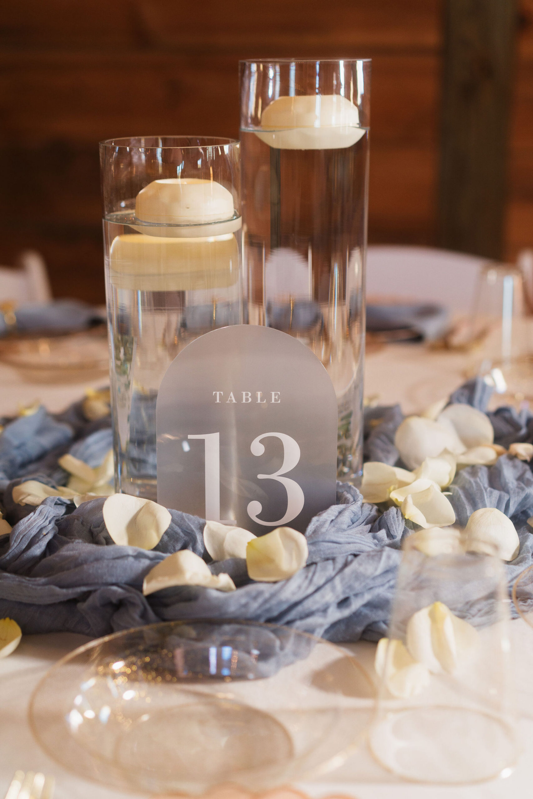 Ana & Carter Table 13 acrylic sign with floating candles and dusty blue fabric at Covey Creek
