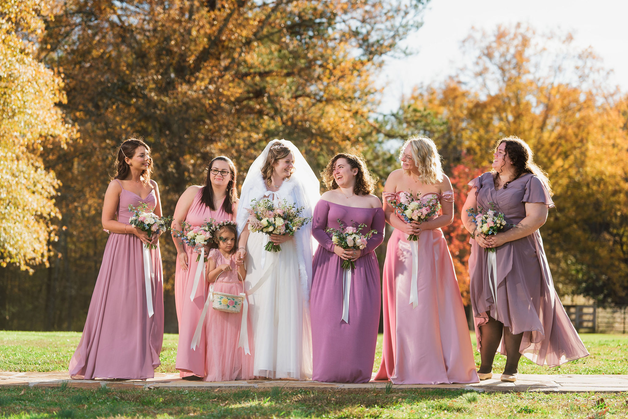 Ana & Carter bridal party laughs on a stone path, blush gowns and autumn trees behind at Covey Creek