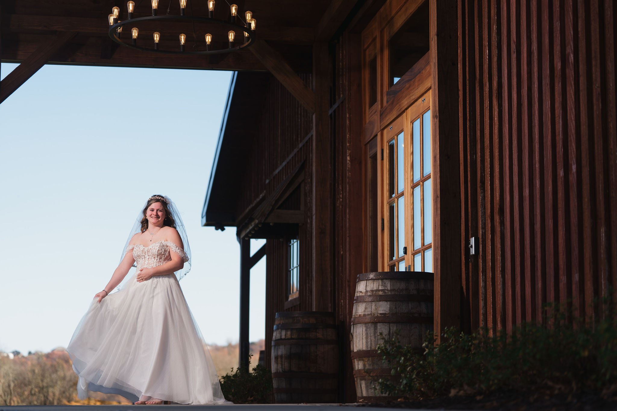 Ana & Carter: Ana poses in her lace gown by the barn doors and hanging chandelier at Covey Creek
