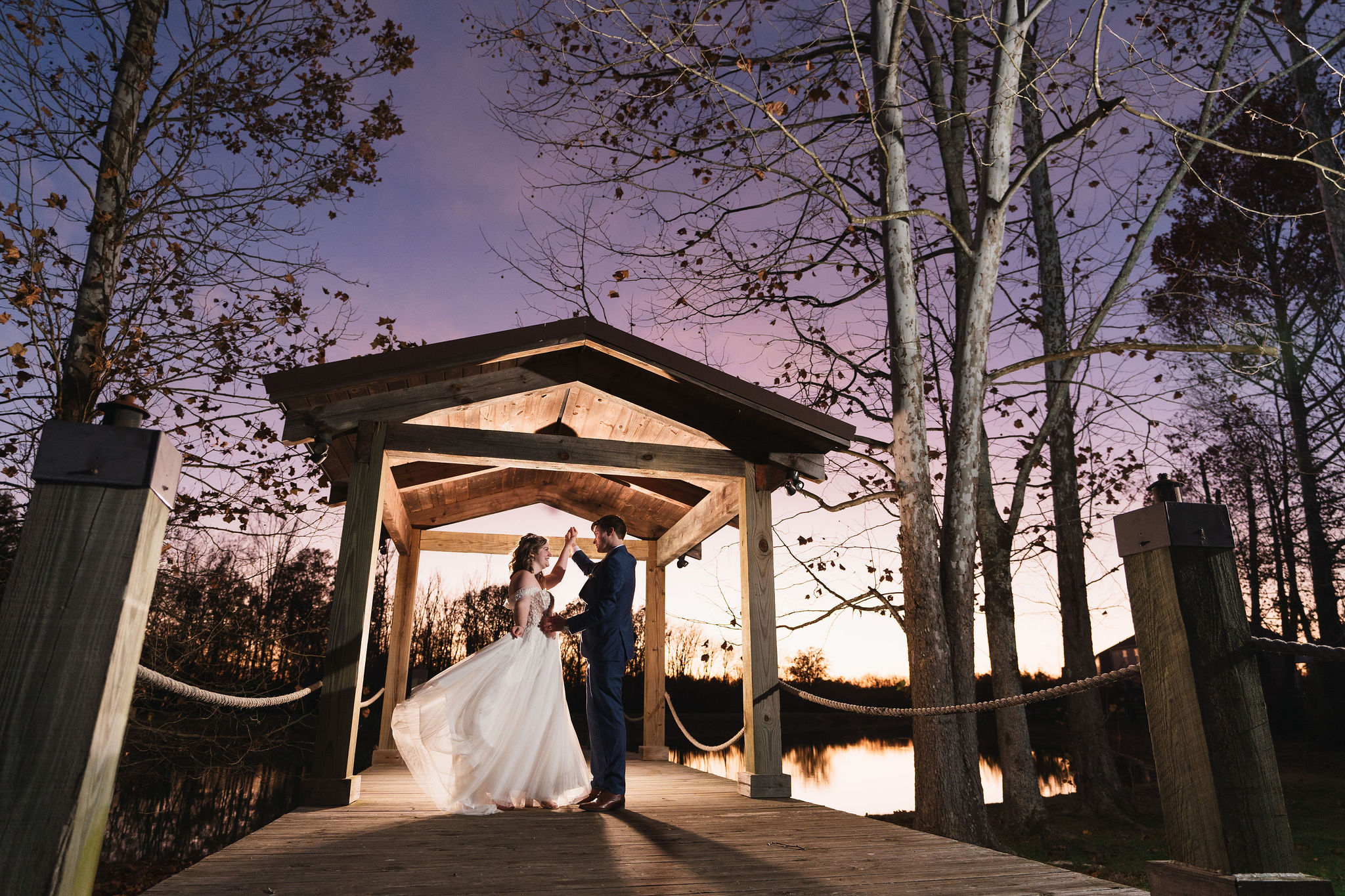 Ana & Carter dance in the Pond pavilion as sunset colors reflect on the water at Covey Creek