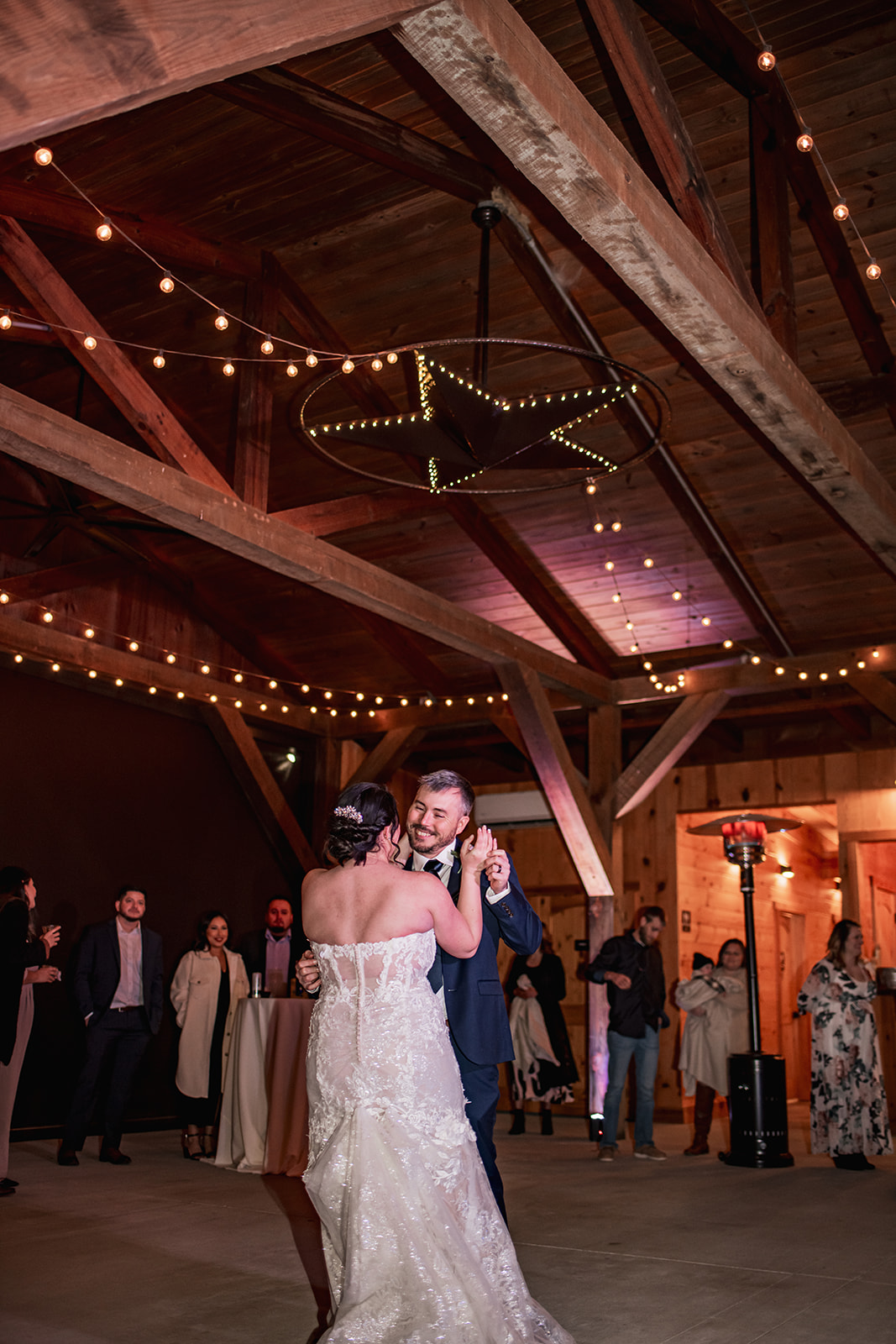 Annie & Will slow-dance under Covey Creek’s star chandelier and bistro lights, her lace train sweeping the concrete floor.