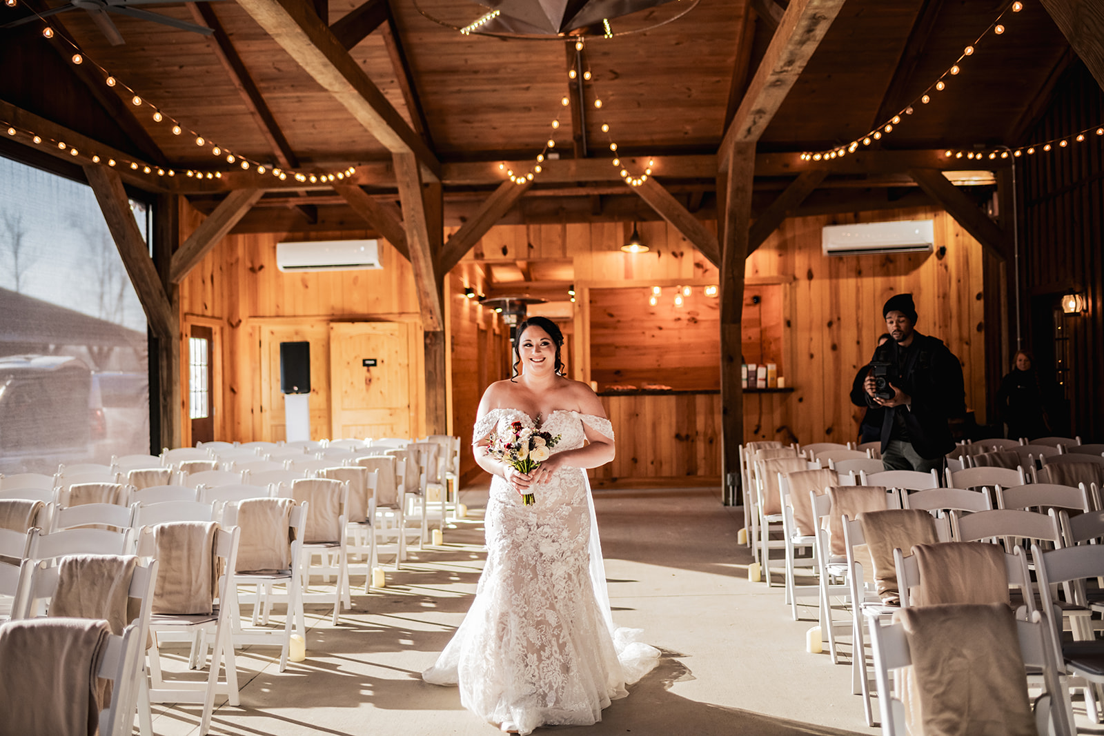Annie walks Covey Creek’s candle-lined aisle in lace at Annie & Will’s ceremony, cream shawls on chairs and string lights.