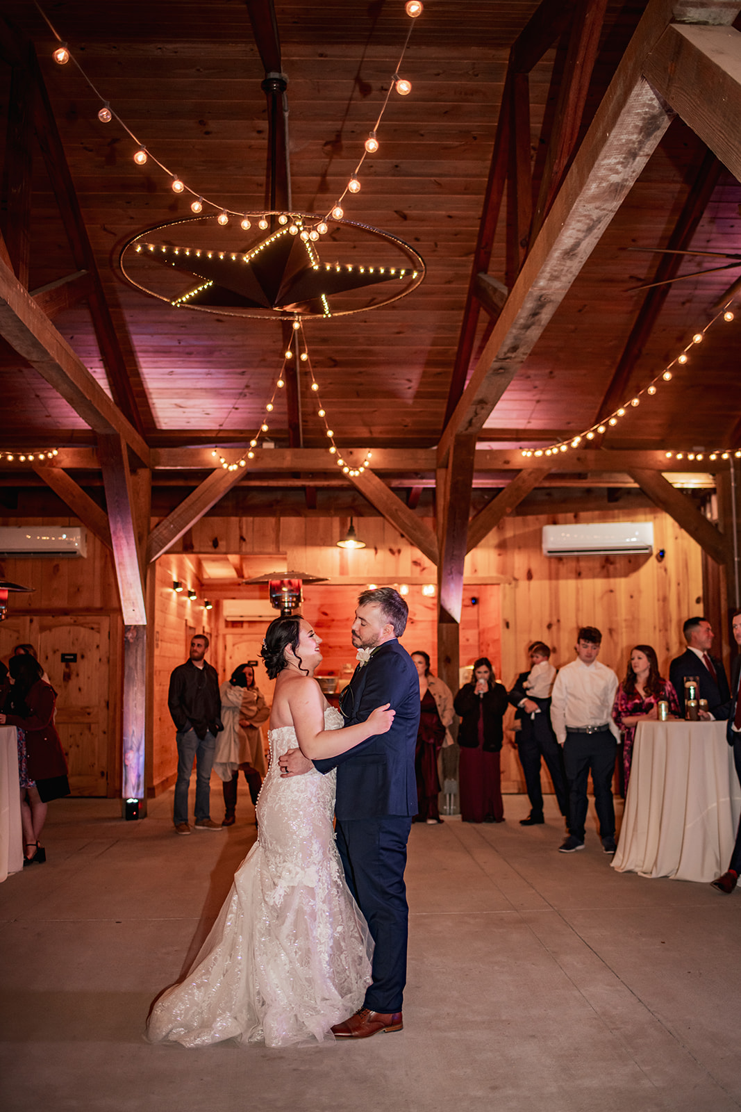 Annie & Will share their first dance under Covey Creek’s lit star fixture, guests watching along the wood-paneled barn.
