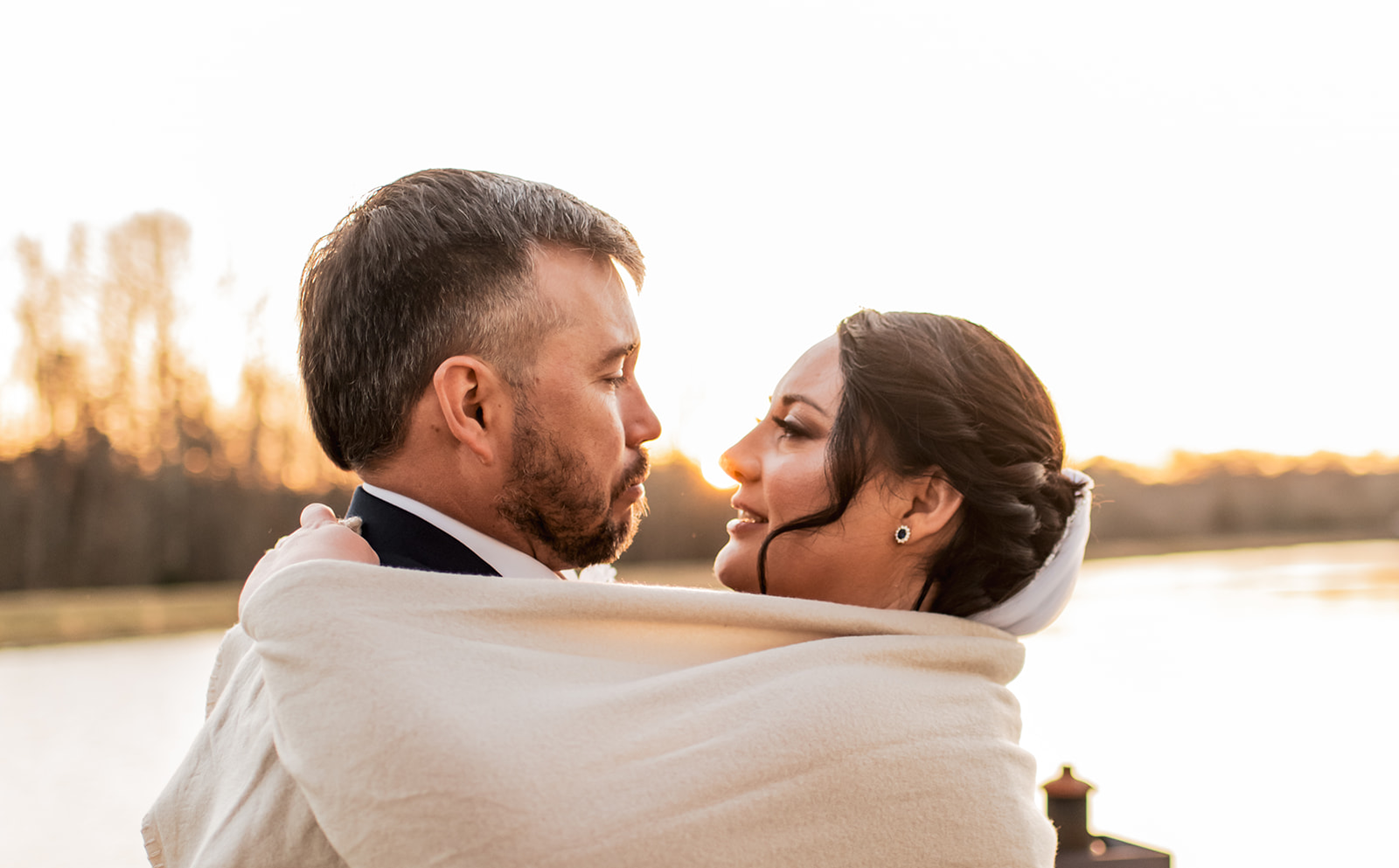 Annie & Will wrap in a cream blanket by Covey Creek’s pond at sunset, foreheads nearly touching in golden light.