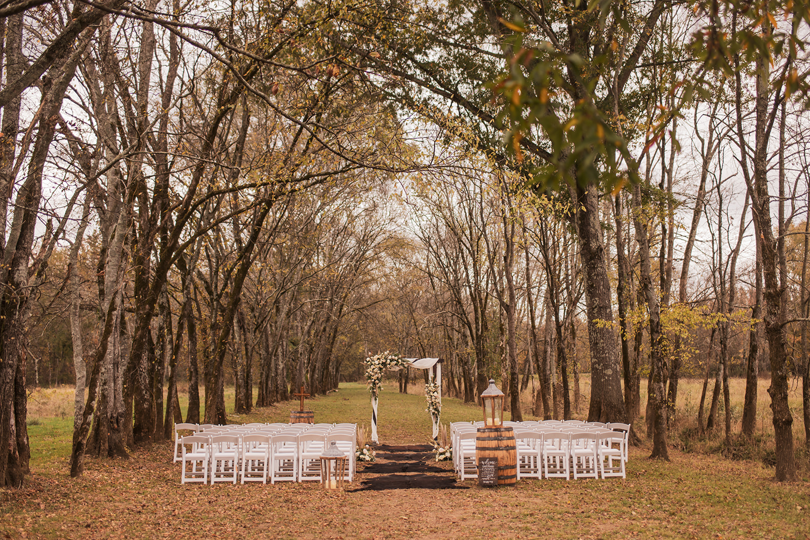 Fall Tunnel of Love aisle at Covey Creek for Isabelle & Alex—white chairs, rug runner, and floral arch.