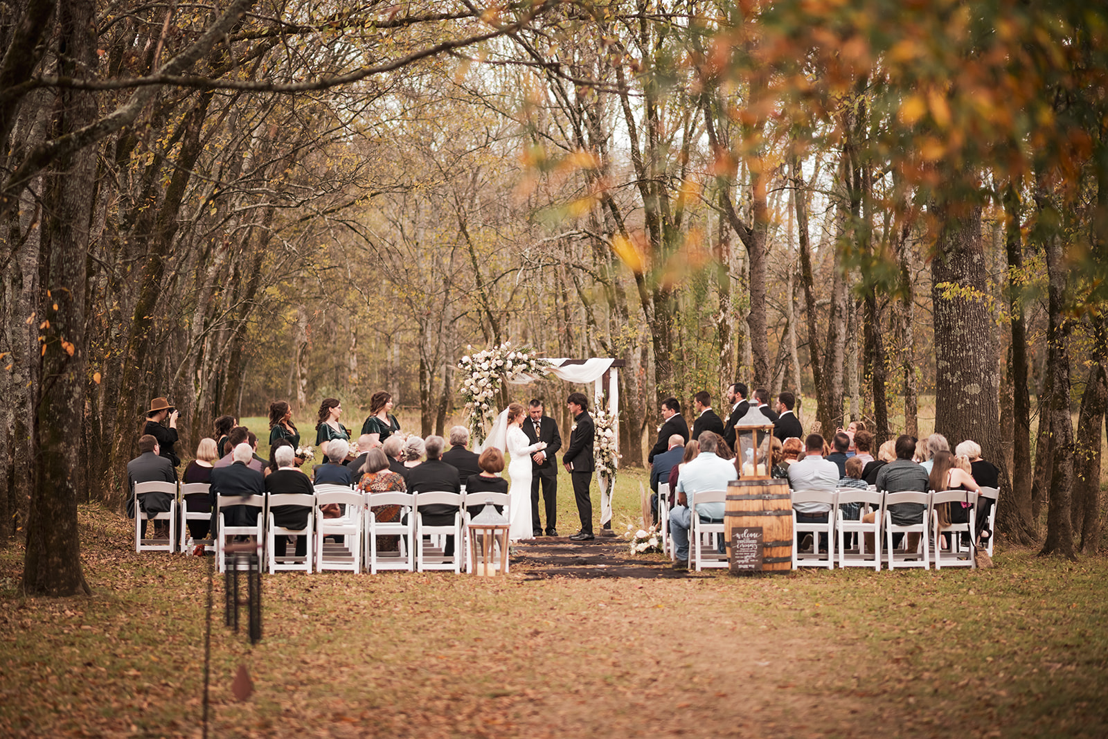 Isabelle & Alex stand under a floral arbor at Covey Creek’s Tunnel of Love ceremony with guests seated.
