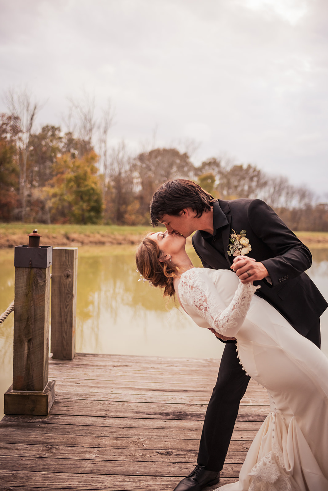 Isabelle & Alex share a dip kiss on the wooden dock over the pond at Covey Creek in autumn.