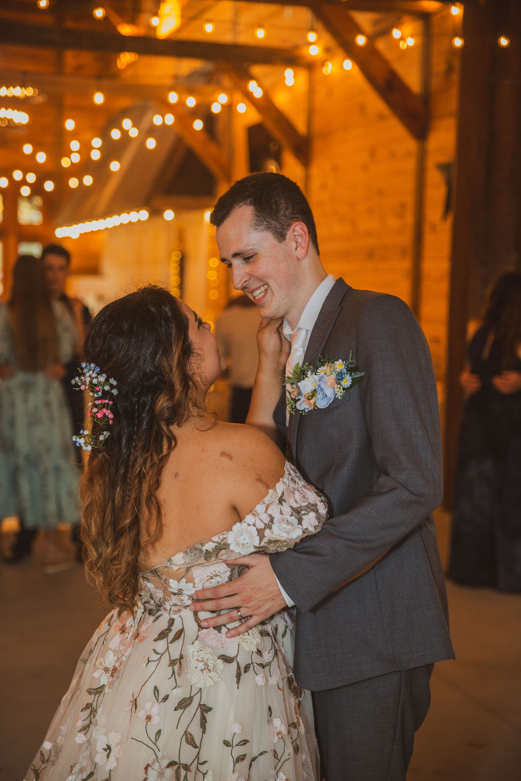 Jen & Alec share a close first dance under warm Edison string lights in the barn at Covey Creek