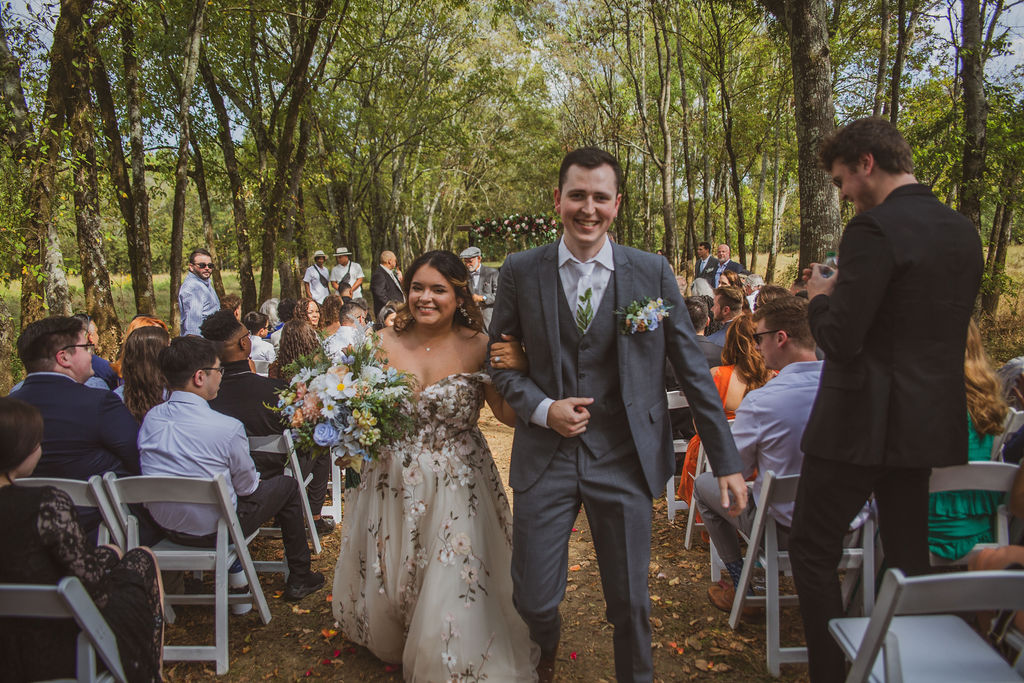 Jen & Alec smile walking the petal aisle after their Tunnel of Love ceremony at Covey Creek