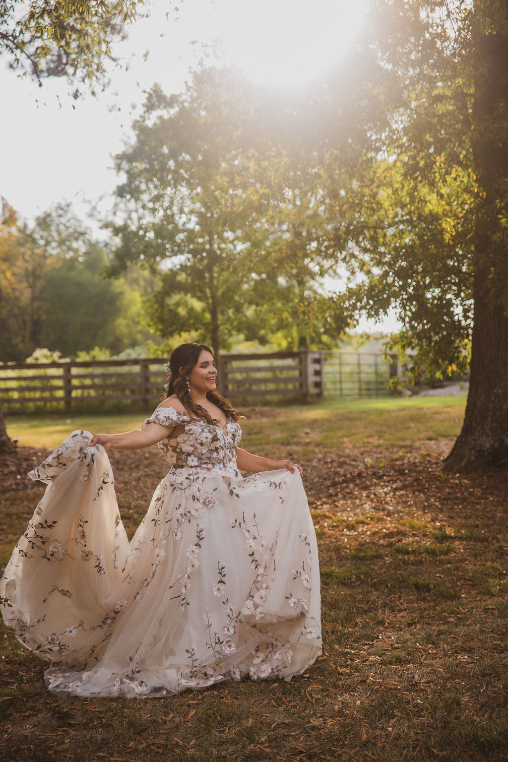 Jen smiles holding her floral-embroidered gown in a golden autumn field for Jen & Alec at Covey Creek