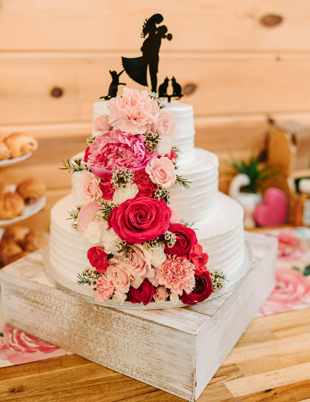 Kate & Josh’s three-tier white cake at Covey Creek with pink-red florals and a couple-and-cats topper