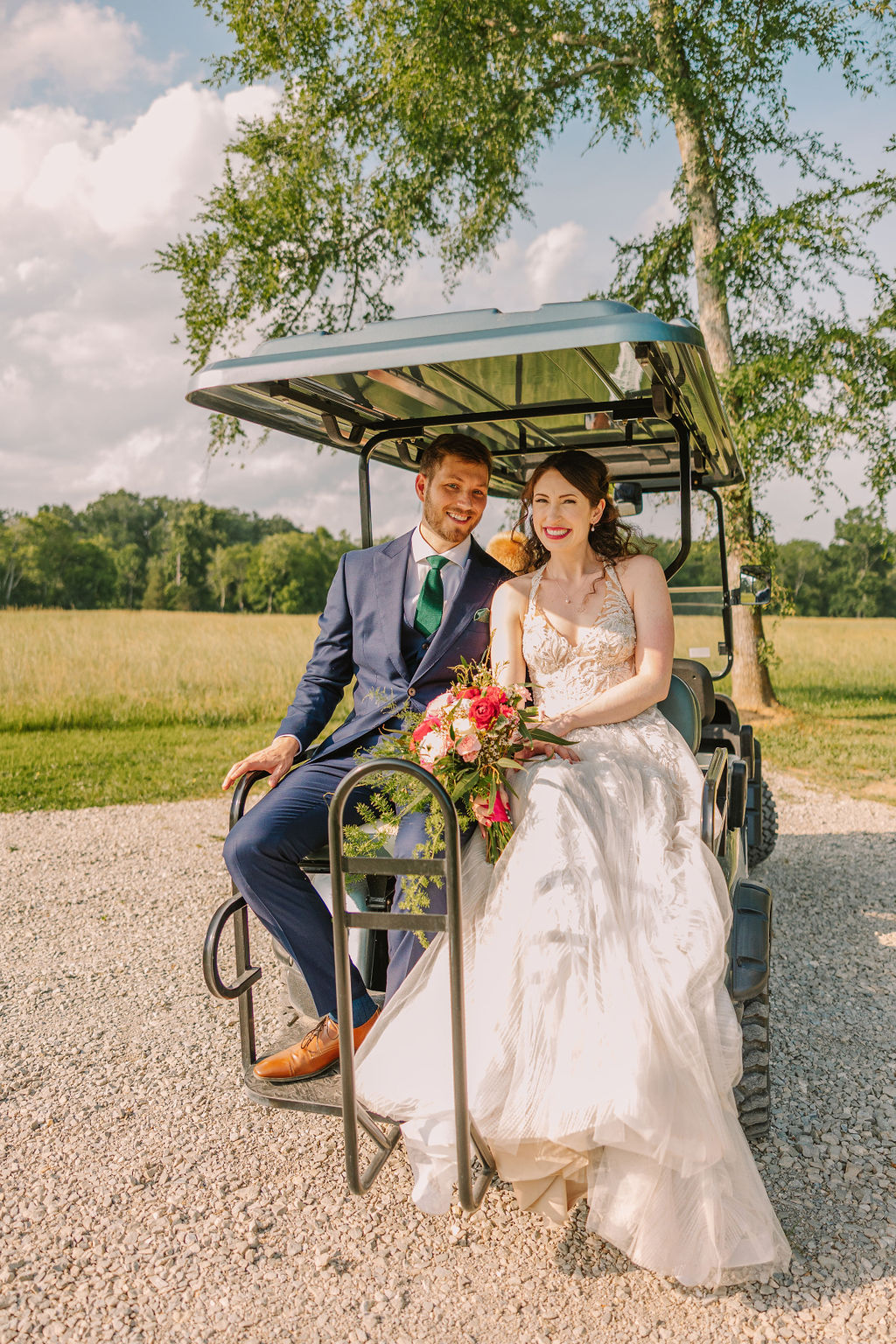 Kate & Josh smile from the back of a golf cart at Covey Creek, pink bouquet and green tie in frame