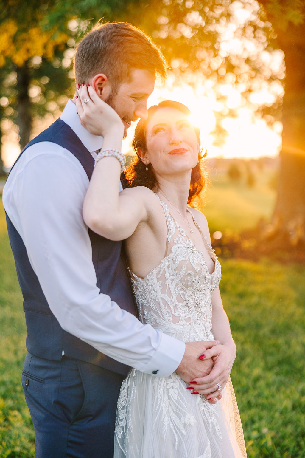 Kate & Josh embrace at golden hour on Covey Creek’s lawn, her lace gown glowing in the sunset