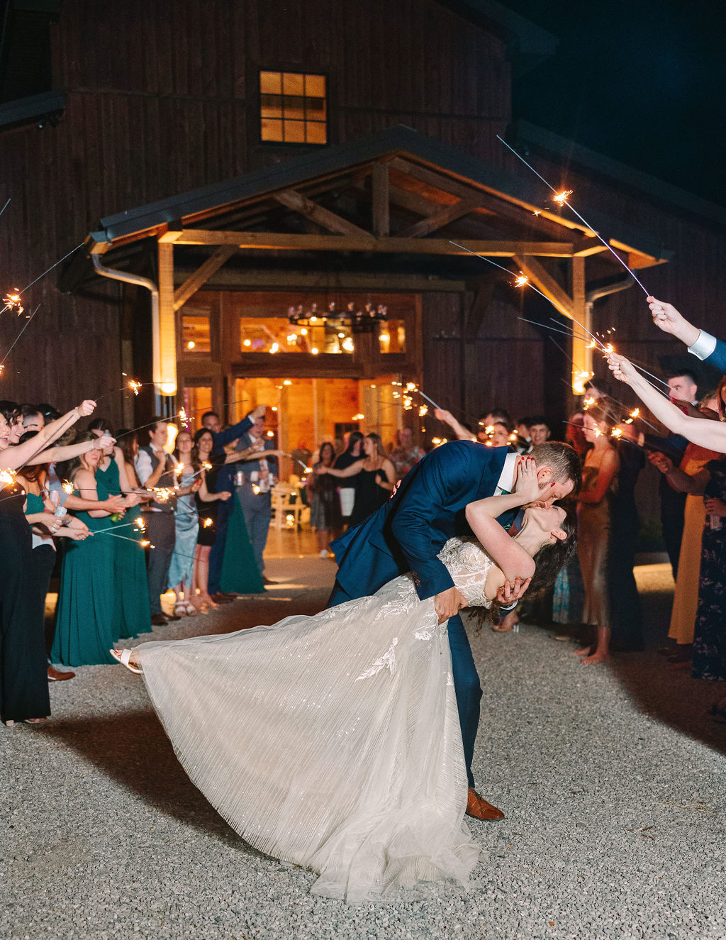 Kate & Josh share a romantic dip kiss in a sparkler send-off outside Covey Creek’s barn at night