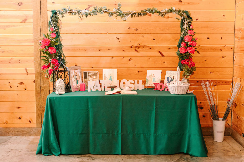 Kate & Josh guest-book table at Covey Creek with wooden name letters, pink peonies, and sparkler bucket