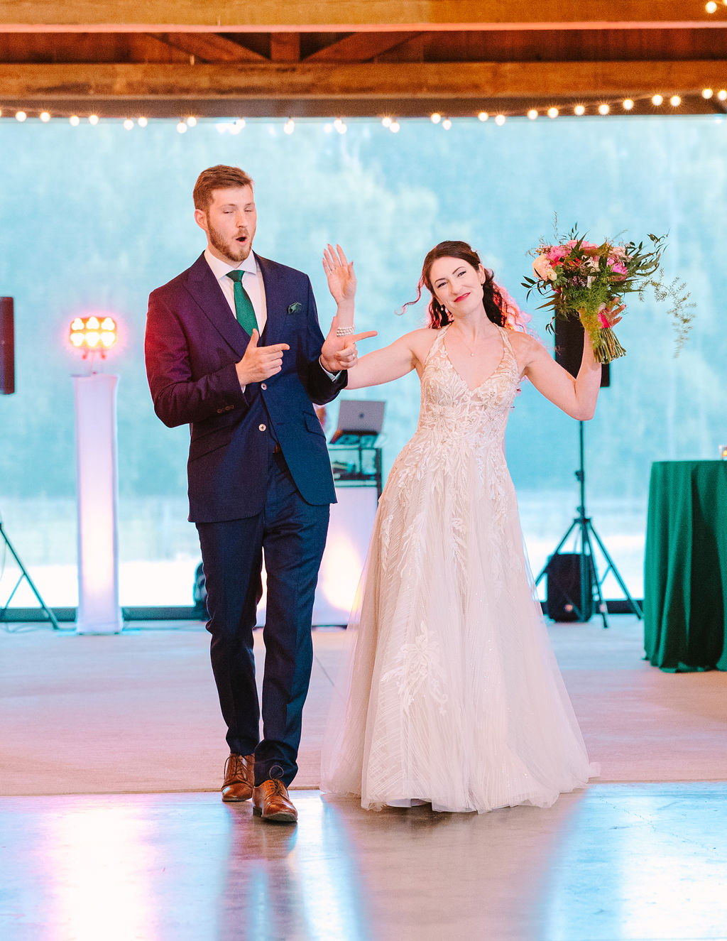 Kate & Josh make a playful reception entrance at Covey Creek, bouquet raised under Edison lights