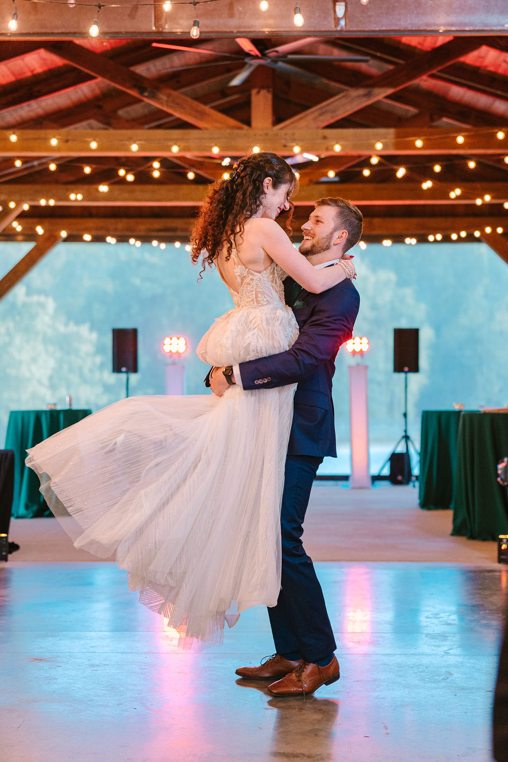 Josh lifts Kate of Kate & Josh on Covey Creek’s pavilion dance floor under glowing string lights
