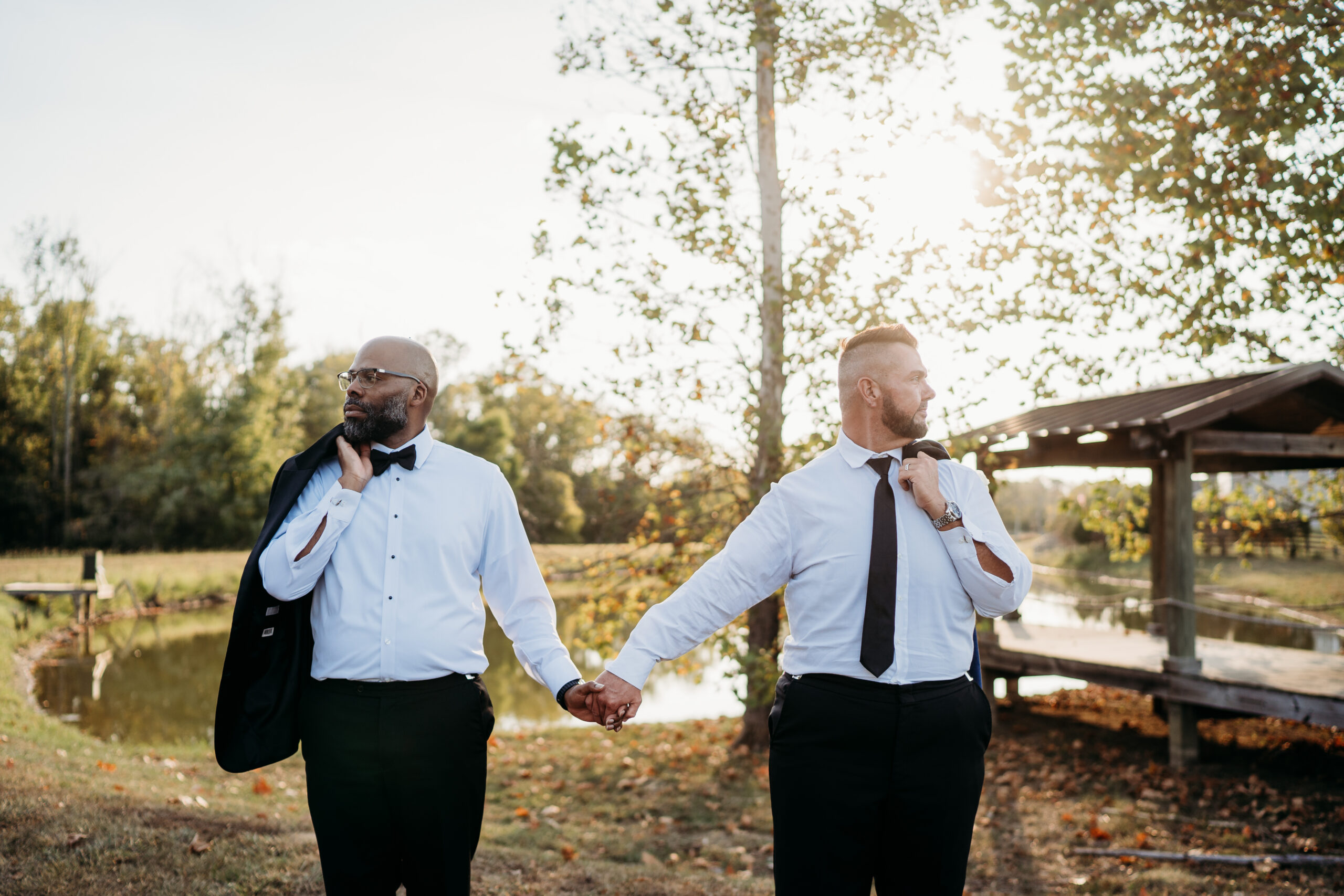 Levi & Billy stand back-to-back jackets over shoulders before Covey Creek Pond at golden hour