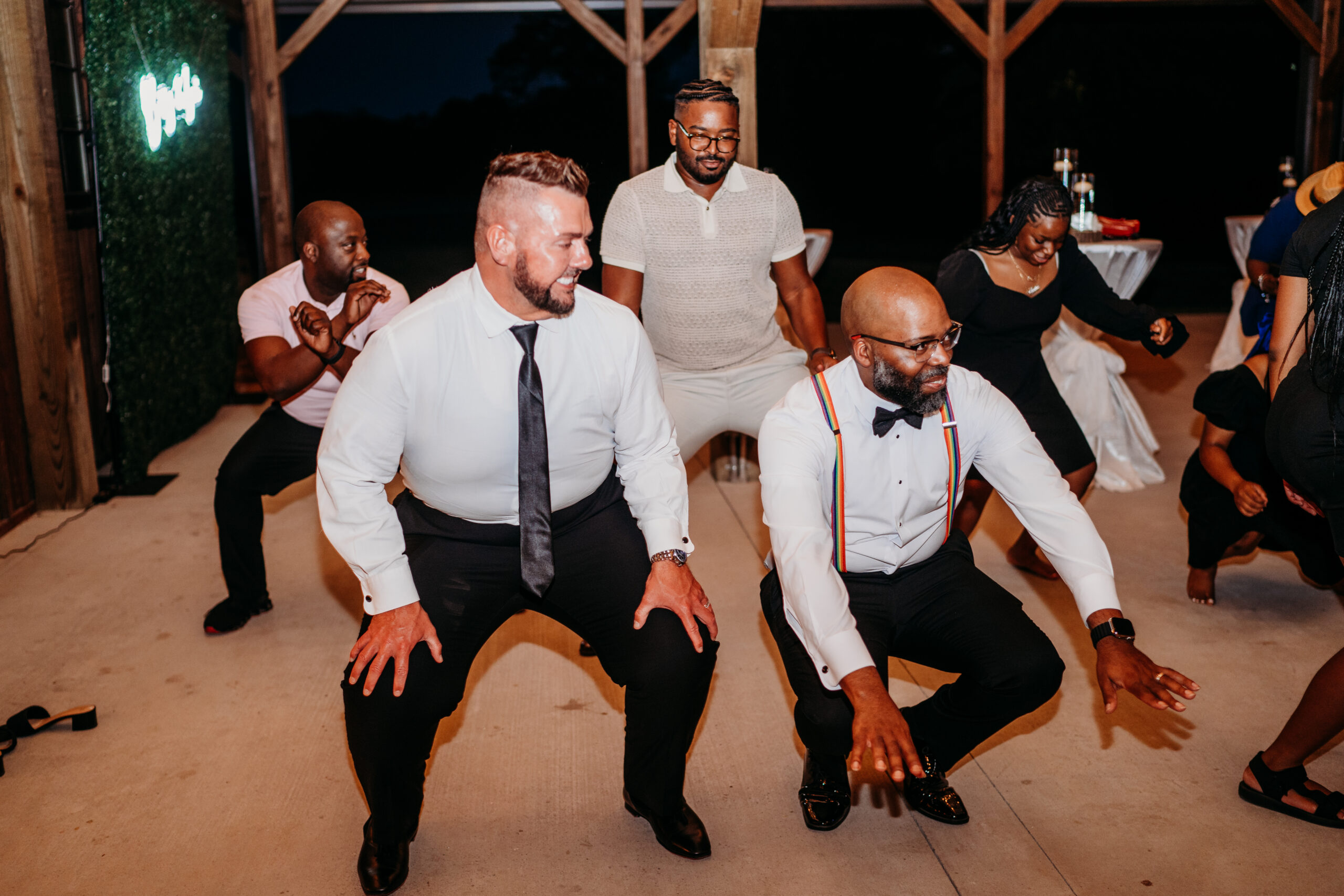 Levi & Billy dance low in a squat under Covey Creek pavilion beams, one in rainbow suspenders