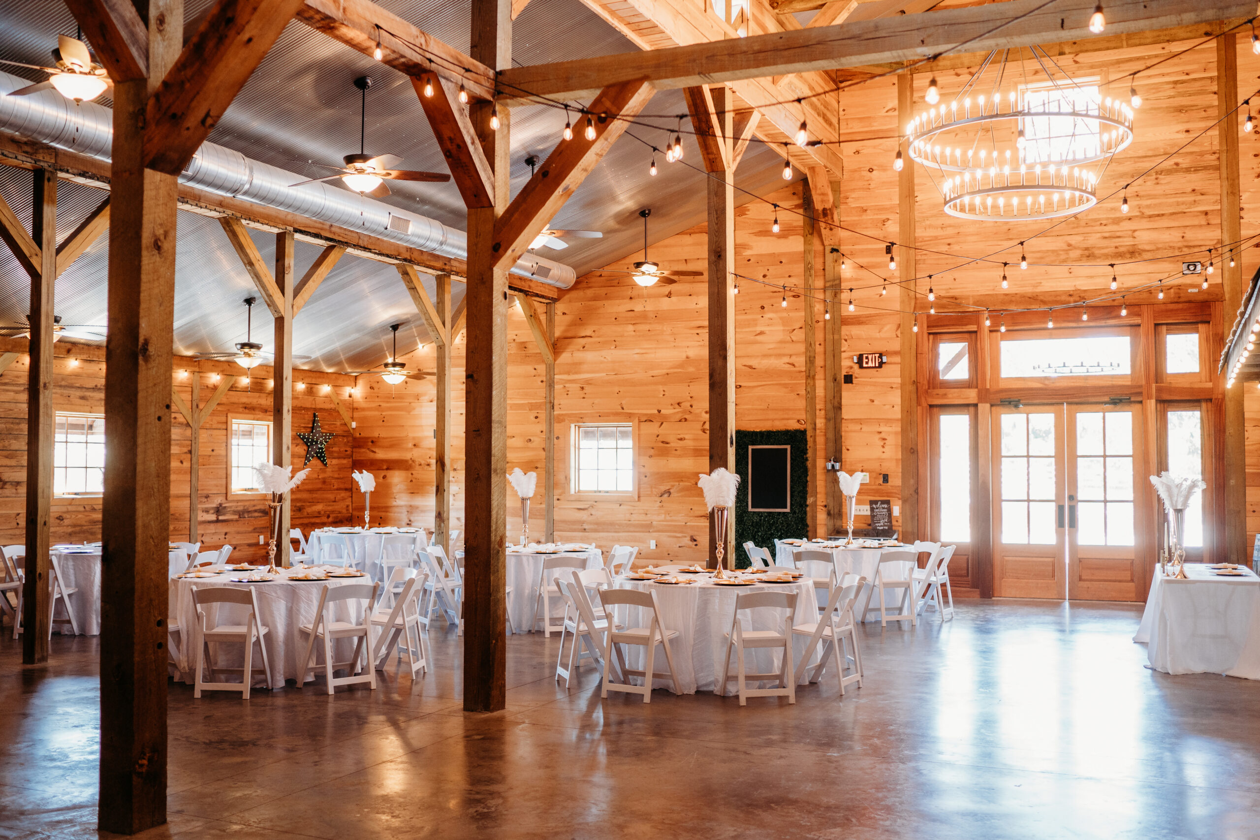 Covey Creek reception hall set for Levi & Billy with gold ostrich-feather centerpieces and string lights