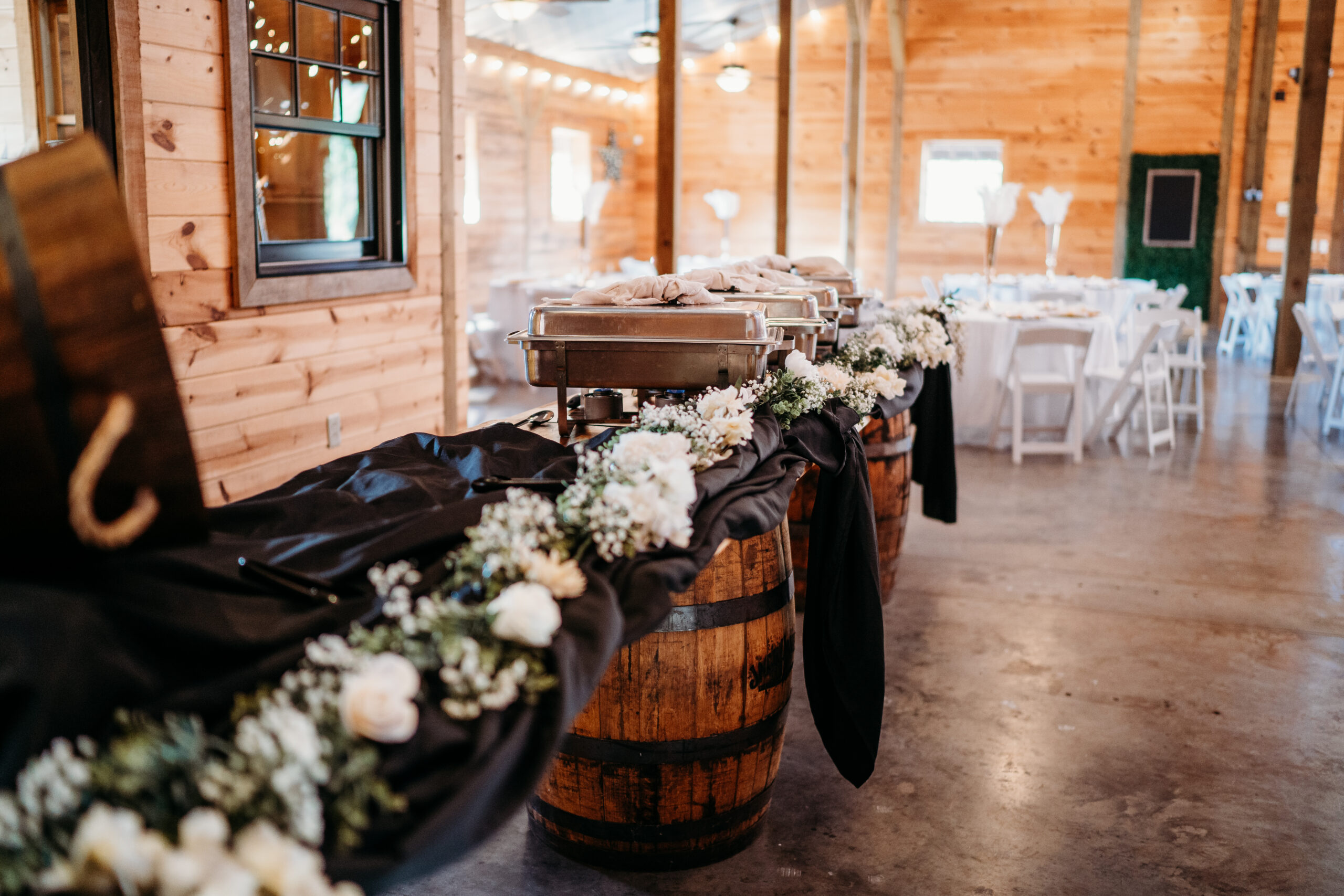 Buffet of chafing dishes on whiskey barrels with white rose garland for Levi & Billy at Covey Creek