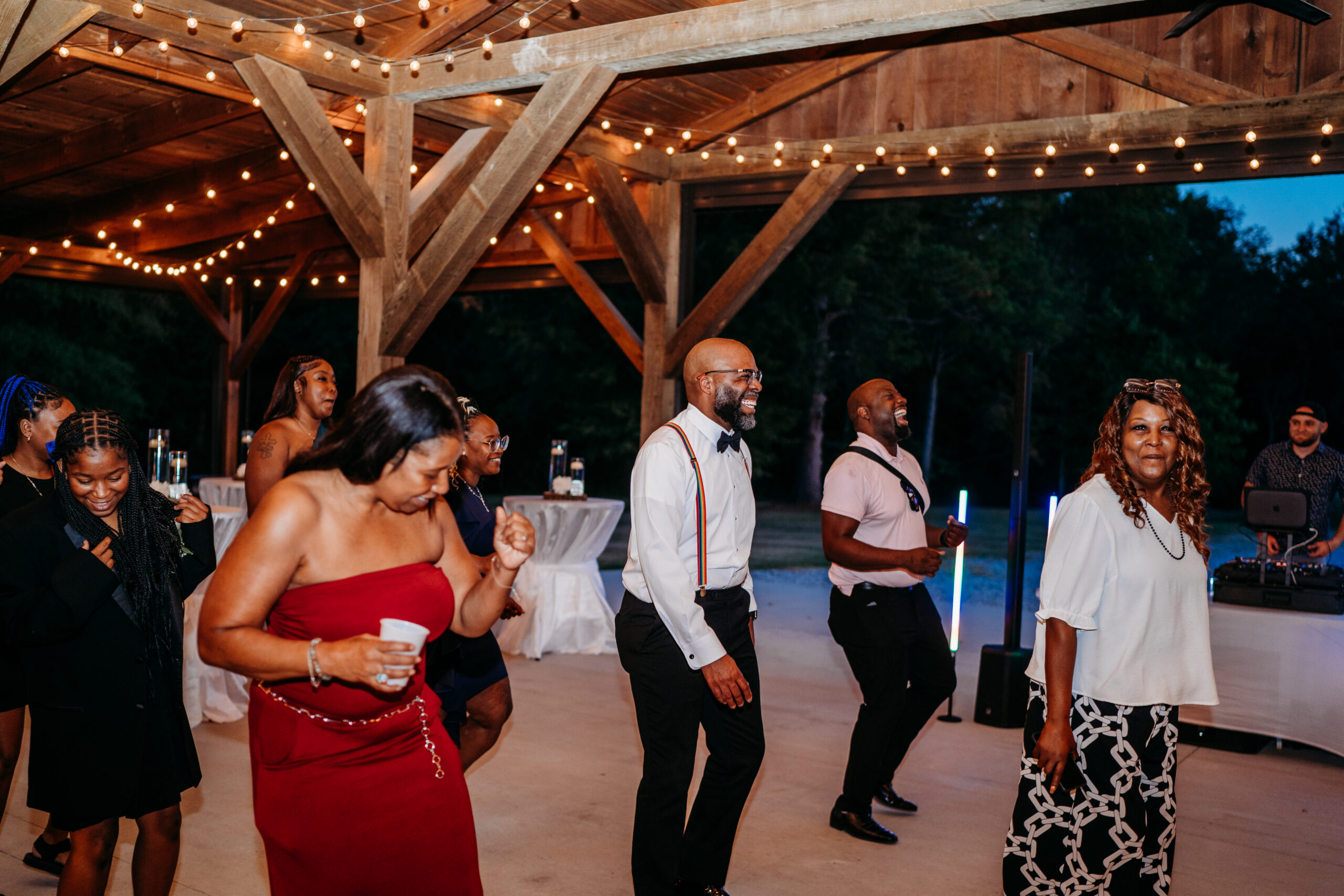 Guests dance under Edison string lights in Covey Creek pavilion at Levi & Billy’s reception