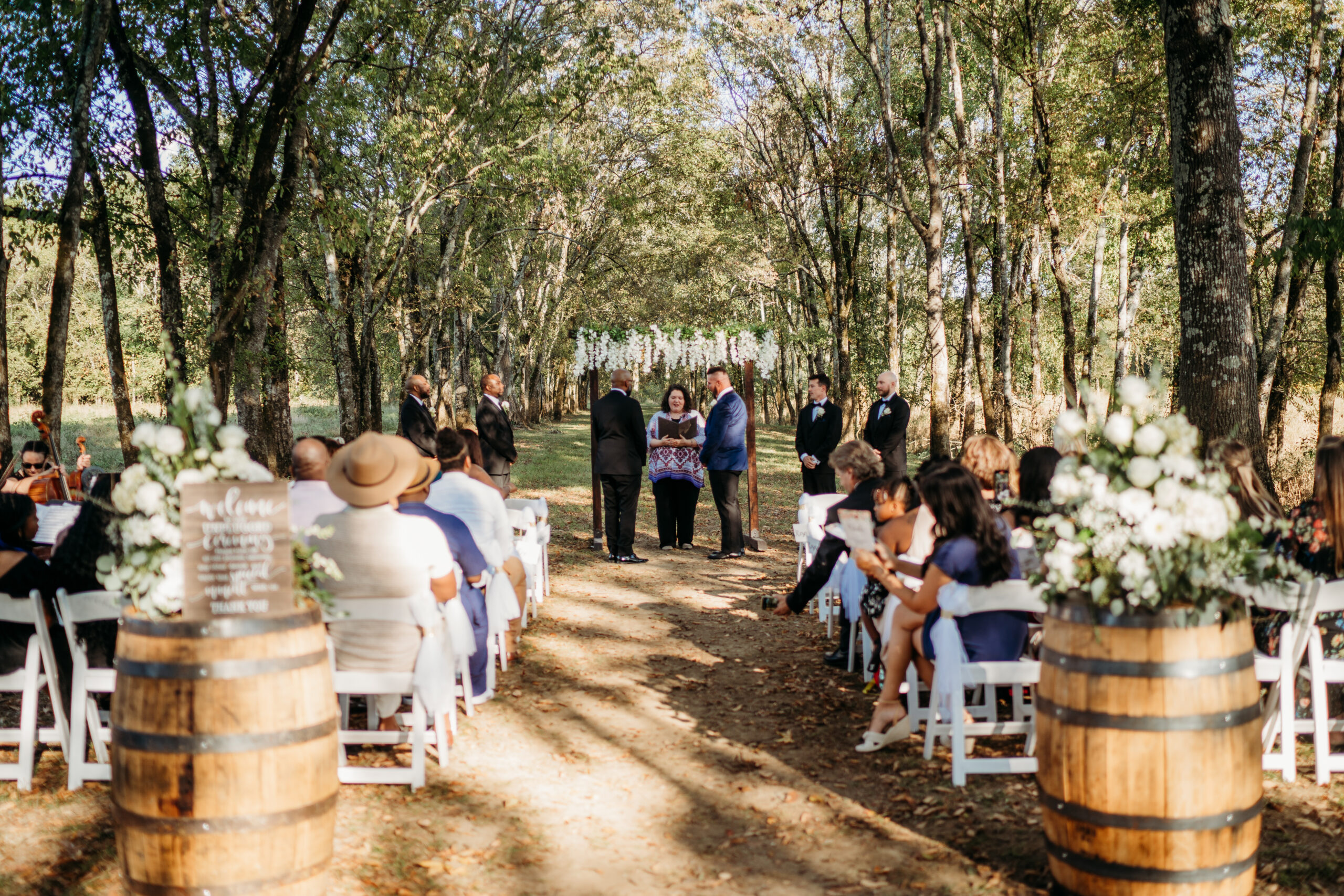 Tunnel of Love aisle for Levi & Billy at Covey Creek with floral barrels and Welcome Forever sign