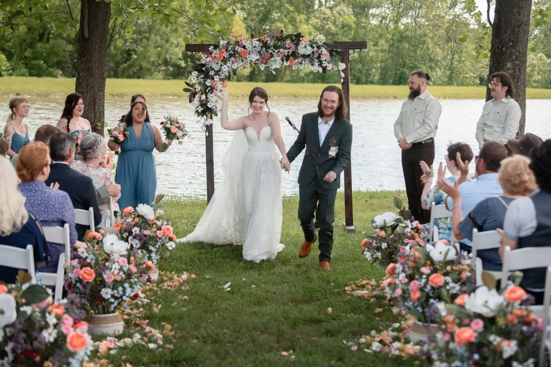 Rachael & Ben recess down the pondside aisle past cheering guests after vows at Covey Creek.