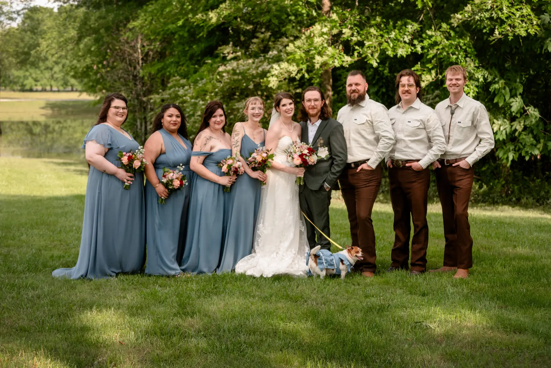 Rachael & Ben with bridesmaids, groomsmen, and their dog on the lawn by the water at Covey Creek.