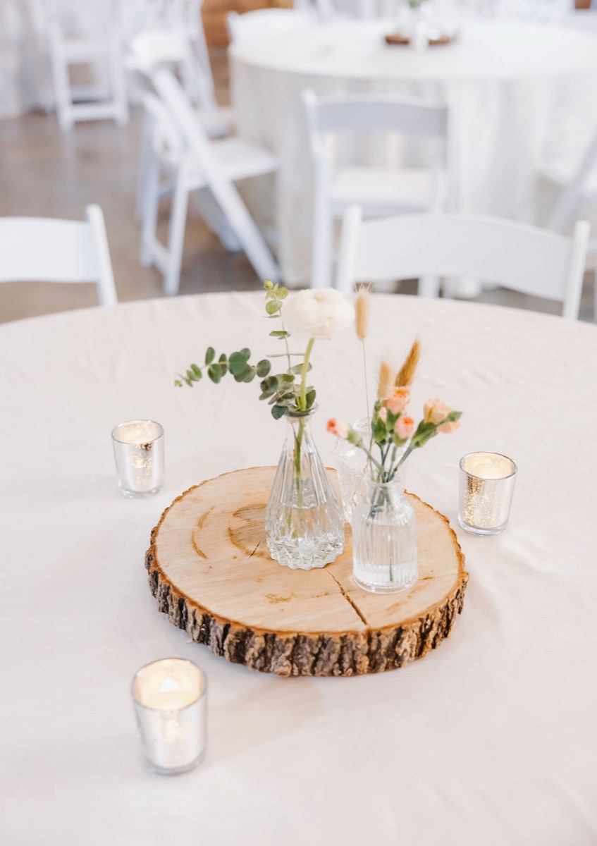 Alexis & Logan reception centerpiece: wood slab, bud vases with ranunculus, and mercury votives at Covey Creek
