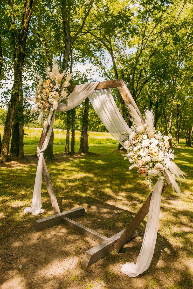 Alexis & Logan floral hexagonal ceremony arch with white draping under the Tunnel of Love at Covey Creek
