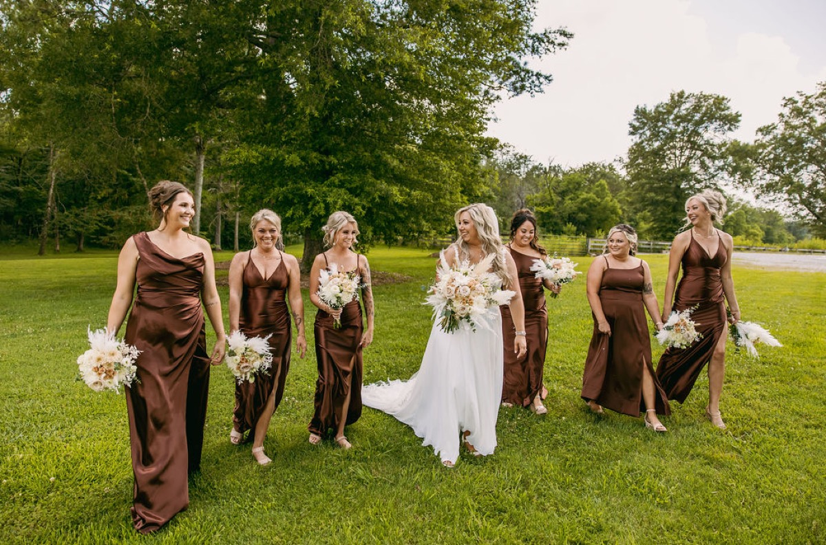 Alexis & Logan: Alexis and bridesmaids in copper dresses walk laughing across the lawn at Covey Creek
