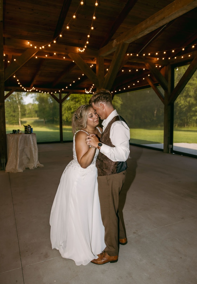 Alexis & Logan slow dance forehead to forehead under fairy lights in the open pavilion at Covey Creek
