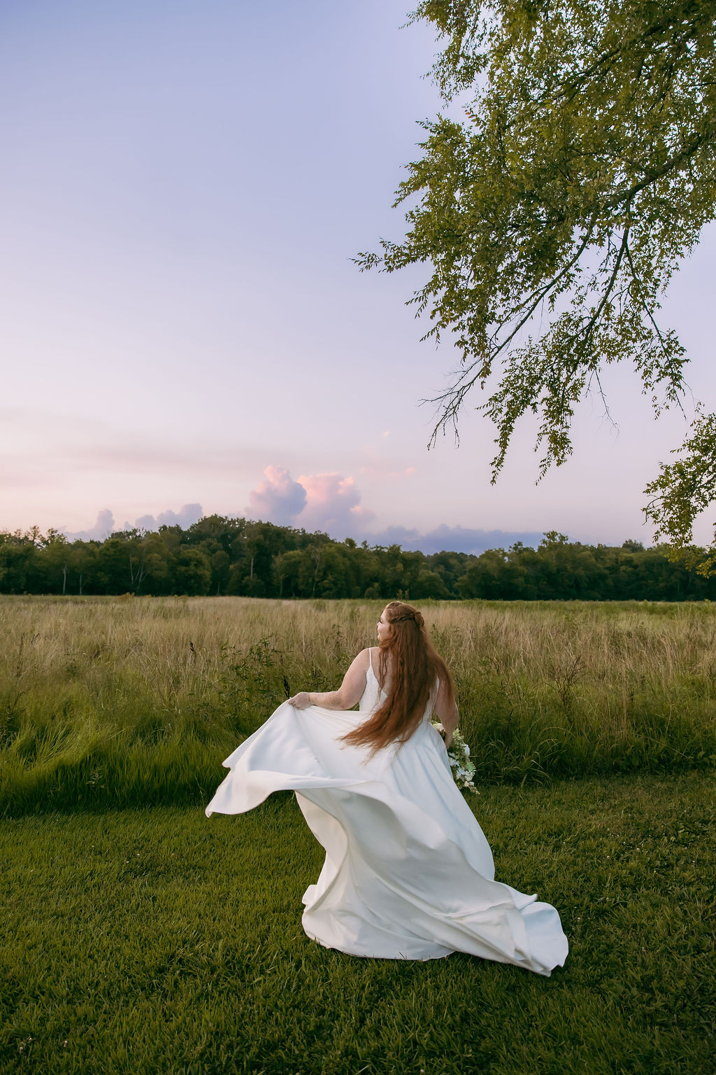 Amanda & Stephen’s bride twirls her white gown in a Covey Creek meadow at dusk under soft pink sky