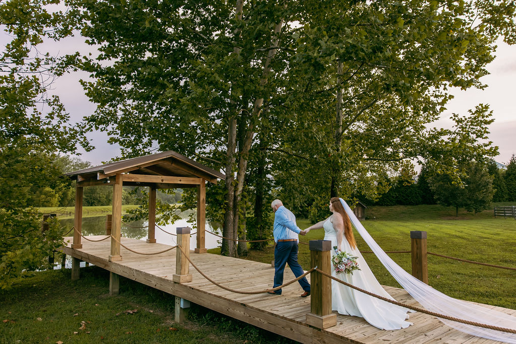 Amanda & Stephen walk Covey Creek’s Pond dock toward the pavilion, her long veil trailing on the planks