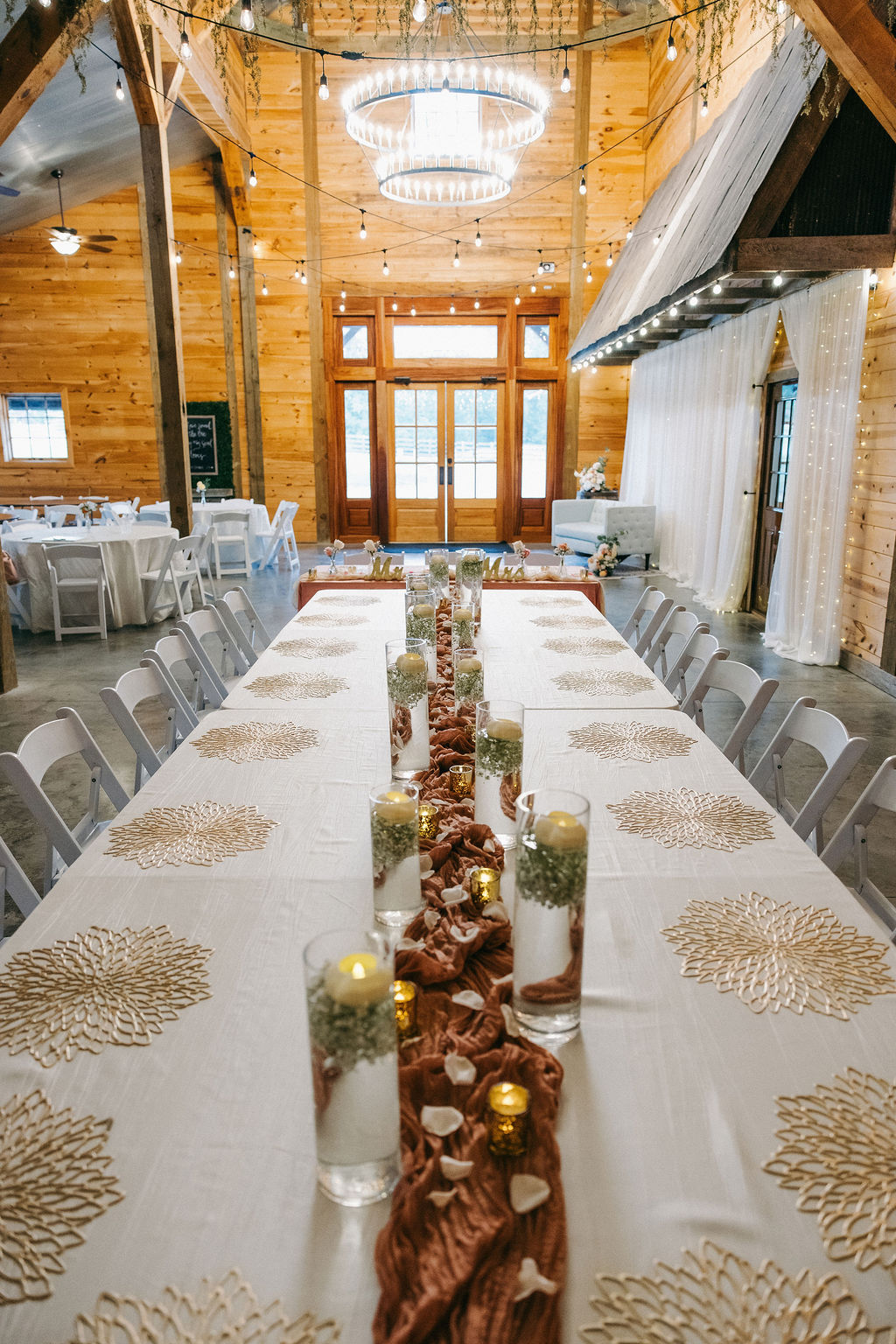 Amanda & Stephen’s long Covey Creek reception table with floating candles, gold placemats, and bistro lights