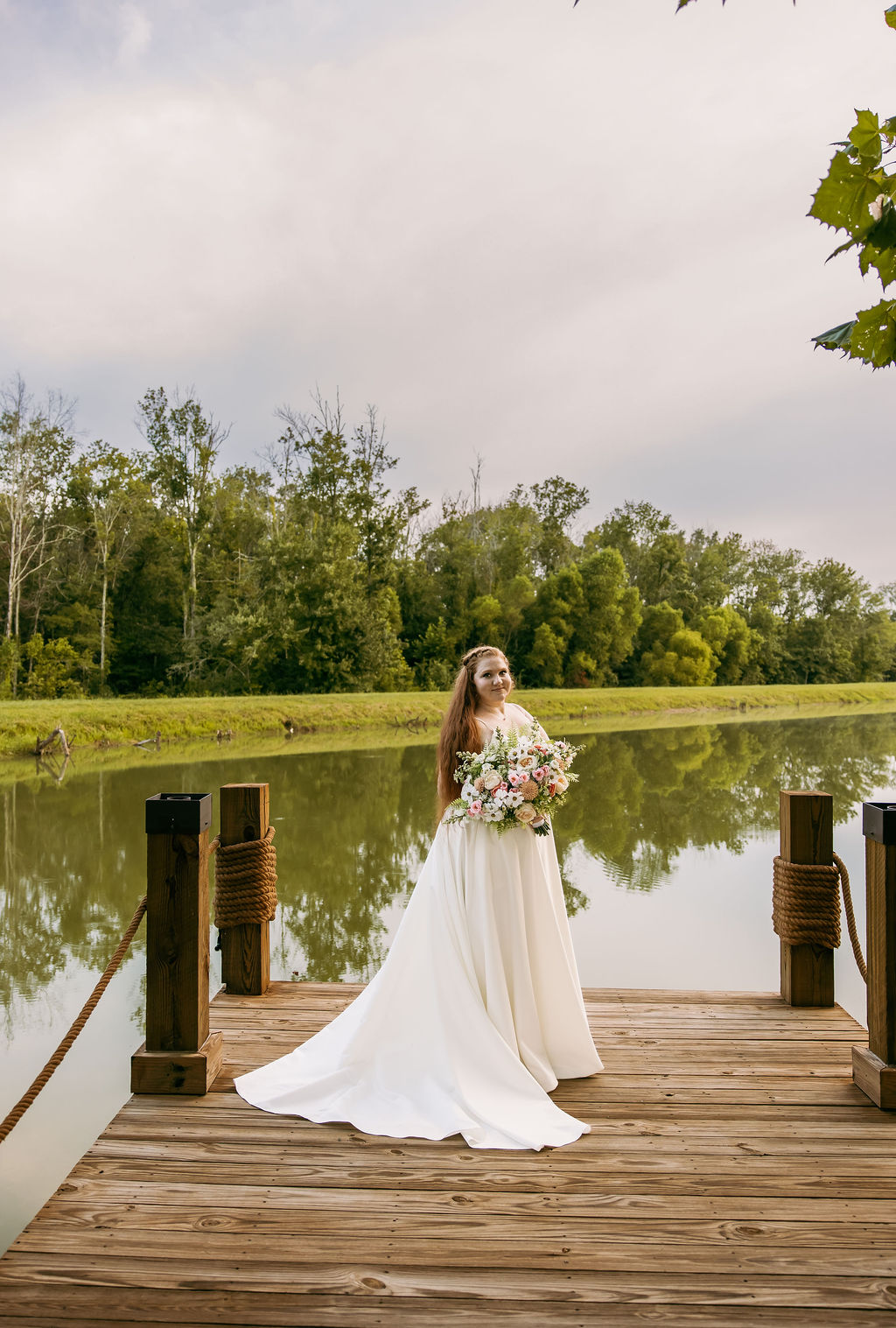 Amanda & Stephen’s bride holds a pink-and-white bouquet on Covey Creek’s Pond dock between rope posts
