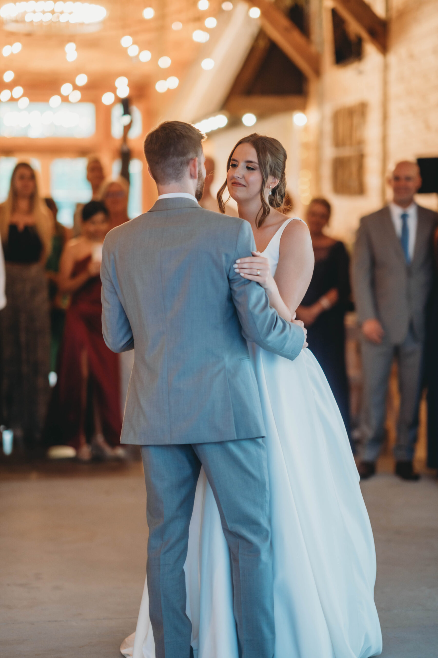 Anna & Jaden share their first dance under warm string lights inside the barn at Covey Creek.