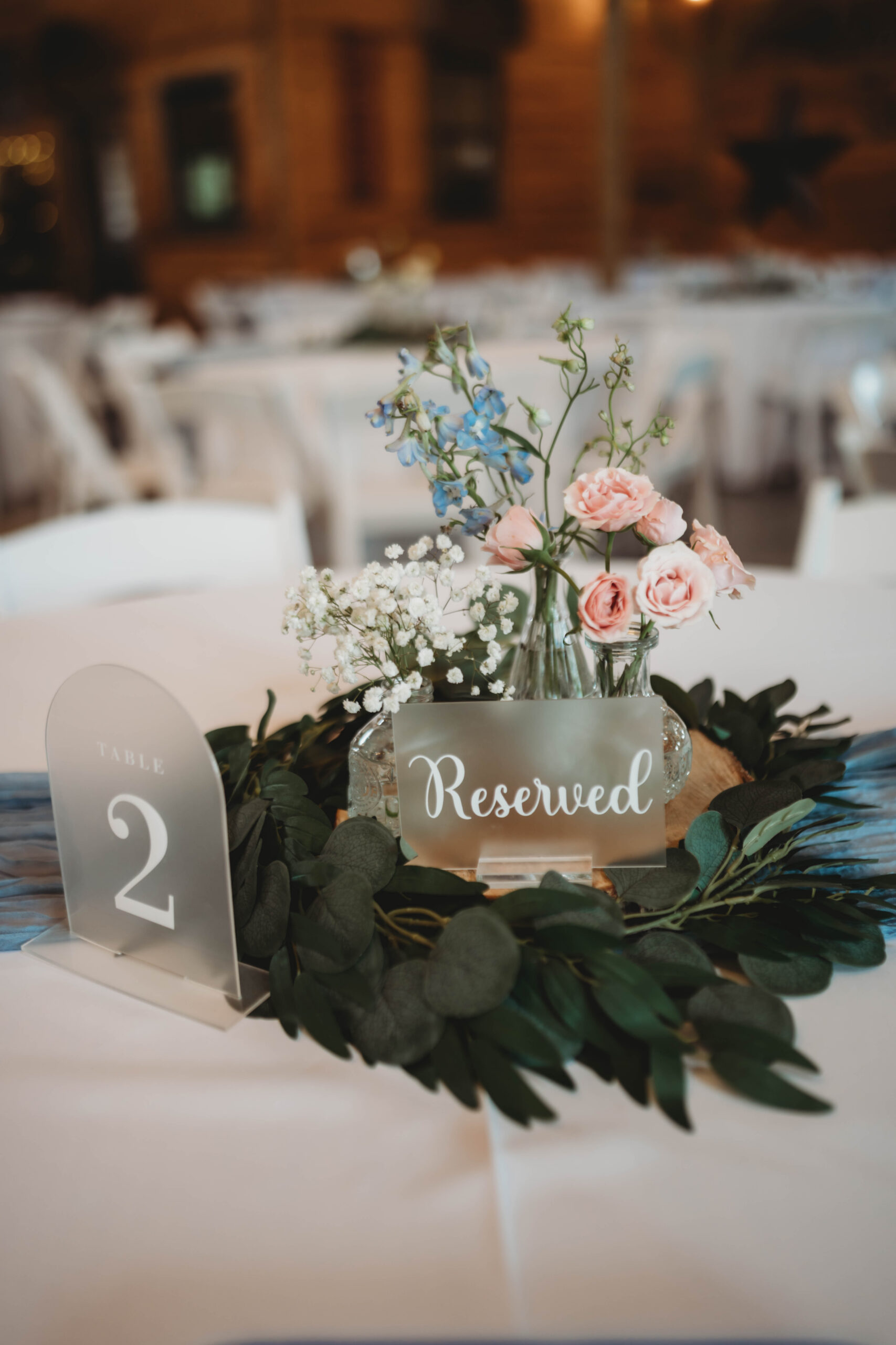 Table 2 centerpiece with bud vases, eucalyptus, and a Reserved sign for Anna & Jaden at Covey Creek.