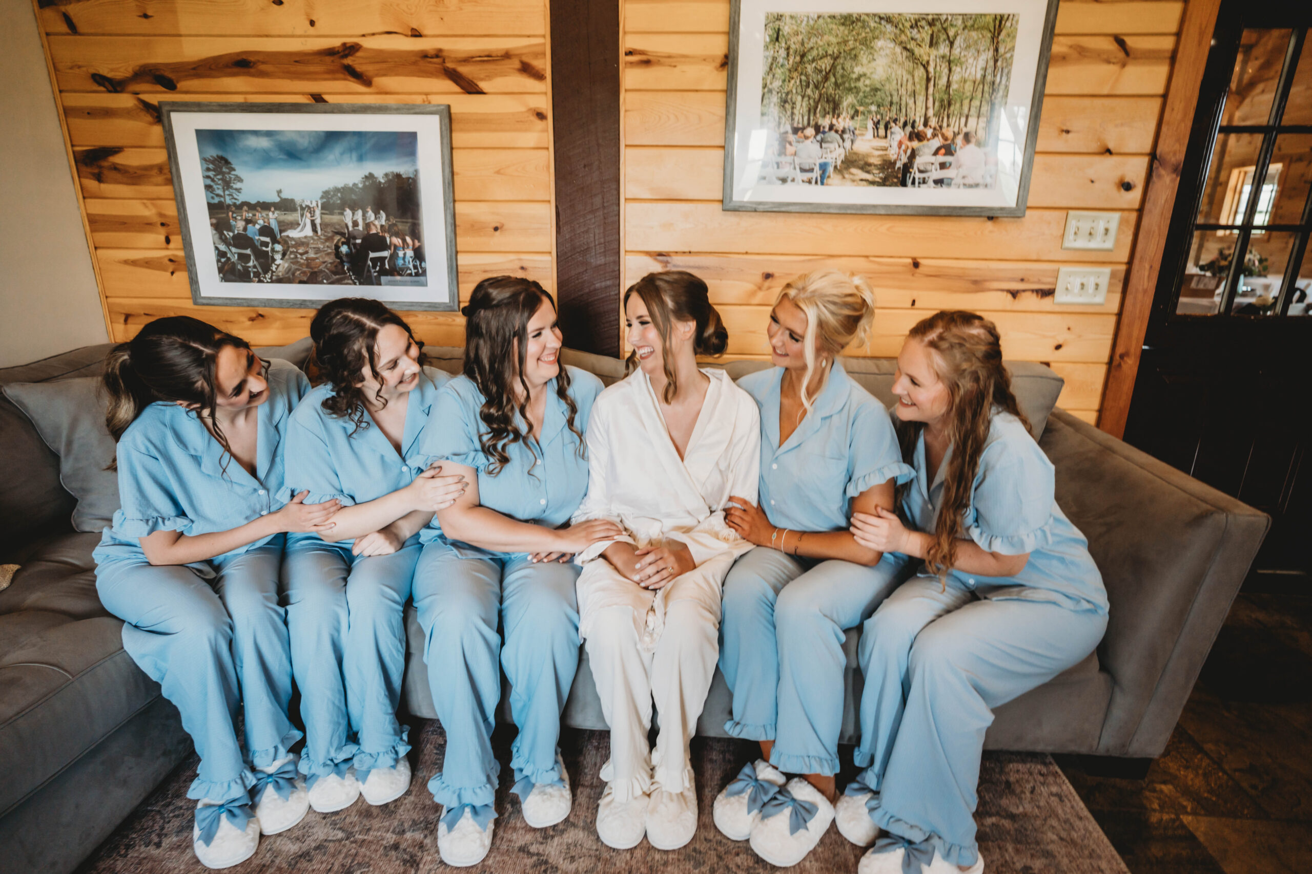 Anna laughs with bridesmaids in blue pajamas on a suite couch for Anna & Jaden at Covey Creek.